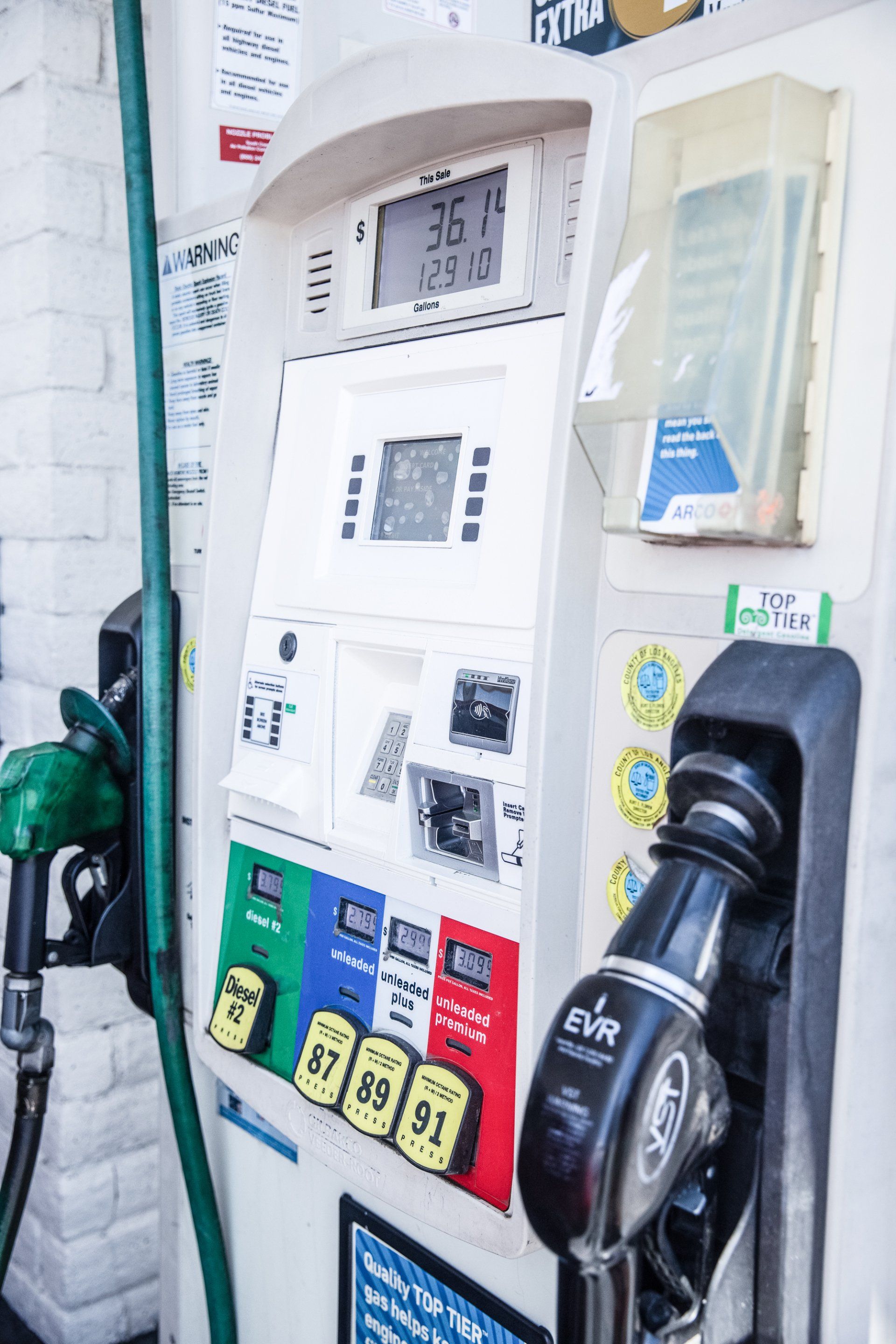 a gas pump at a gas station with a green hose attached to it .