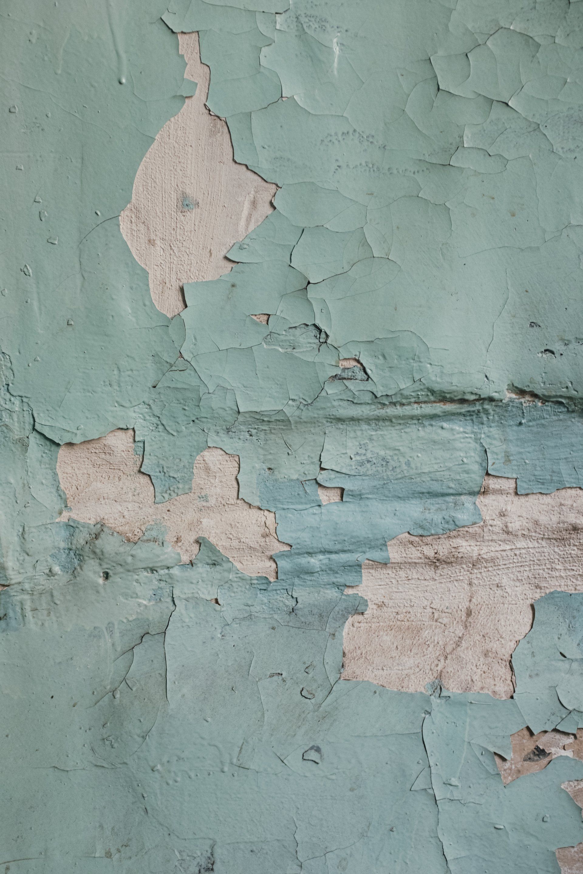 A close up of a wall with peeling paint on it.
