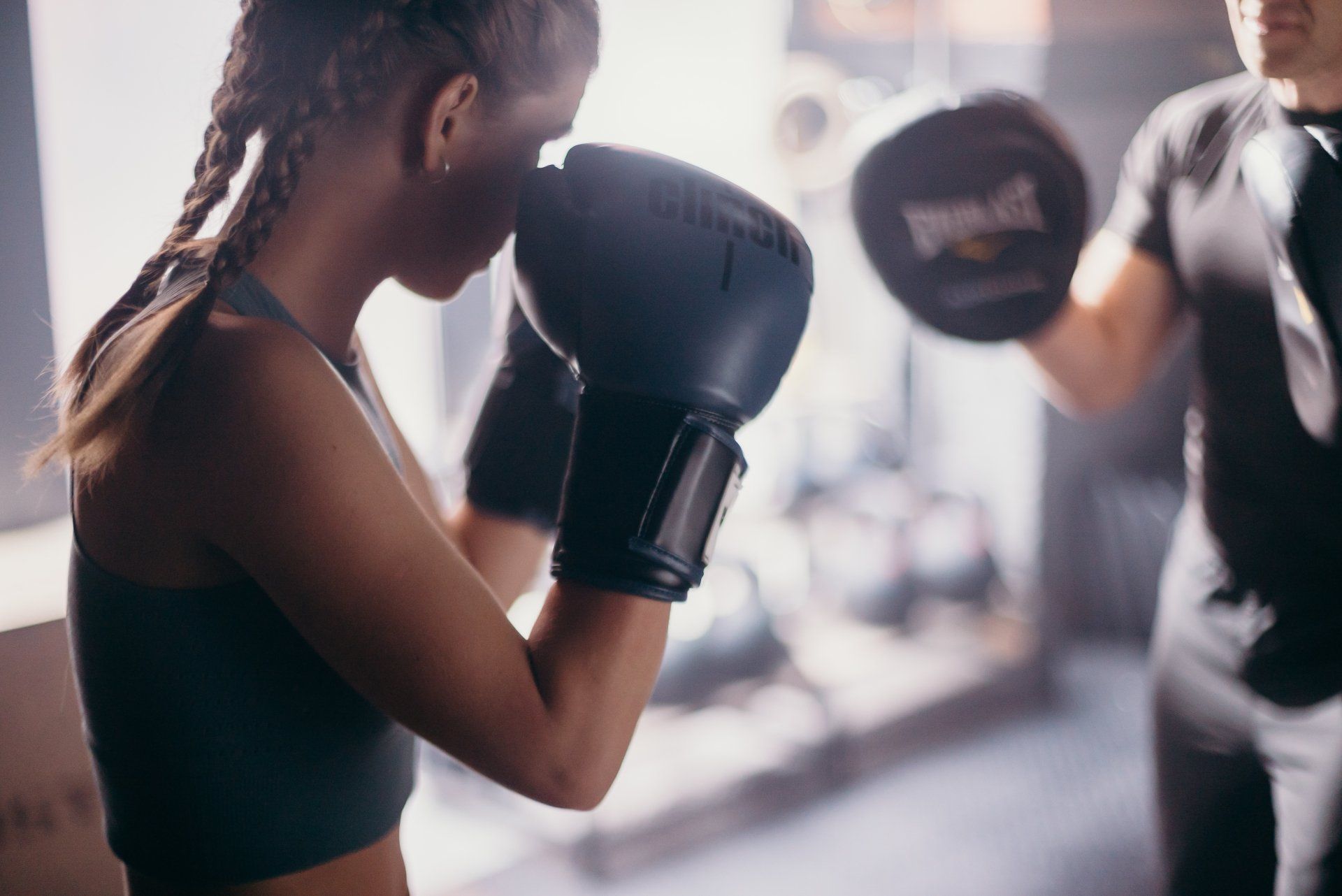 A woman is boxing with a man in a gym.