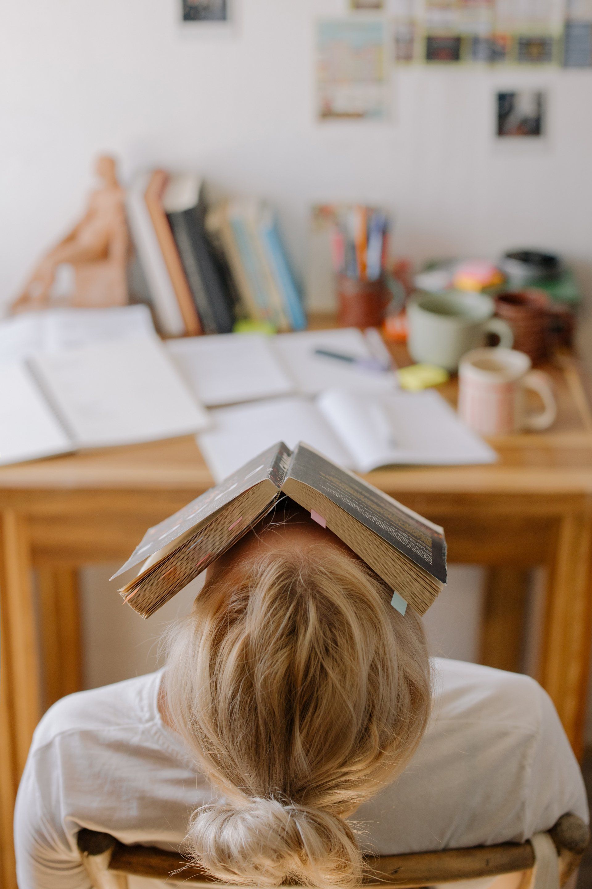 student with book on their face
