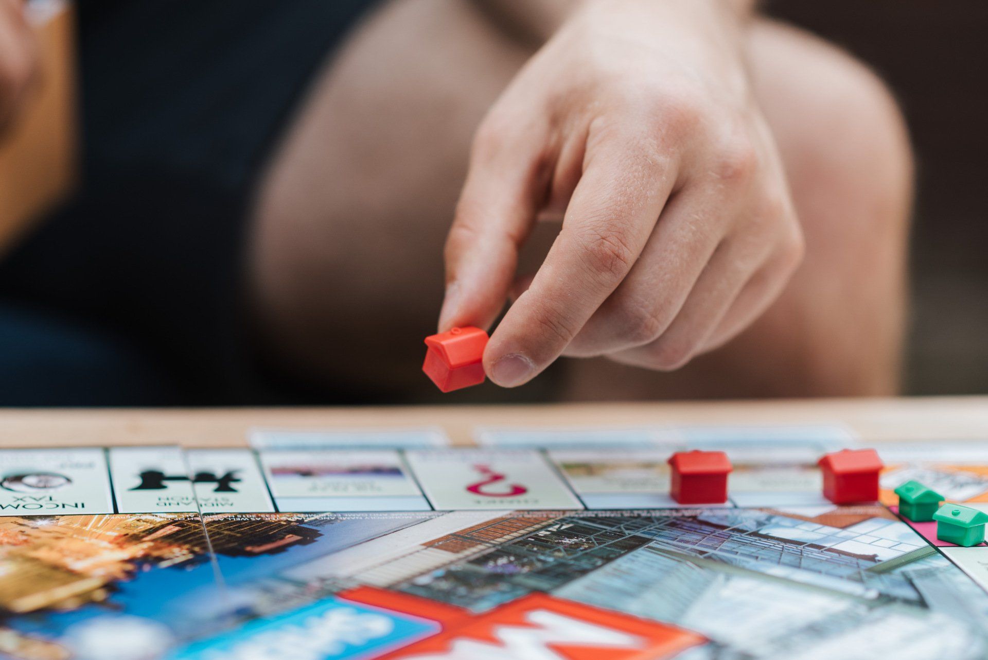 Uma pessoa está jogando um jogo de tabuleiro com uma peça vermelha na mão.