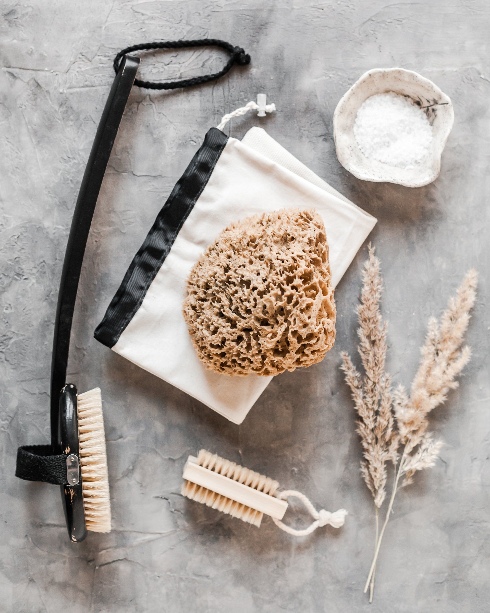 a sponge , brush , towel , and bowl of salt are on a table .