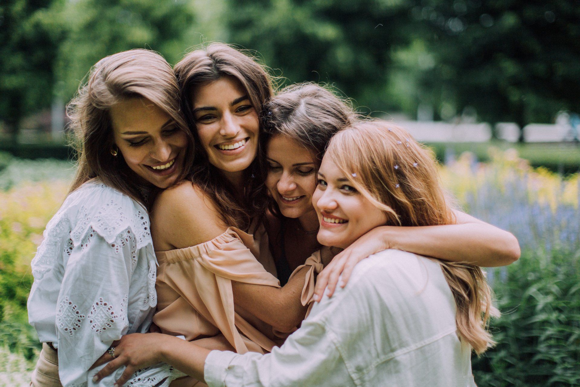 Três mulheres estão se abraçando em um parque.