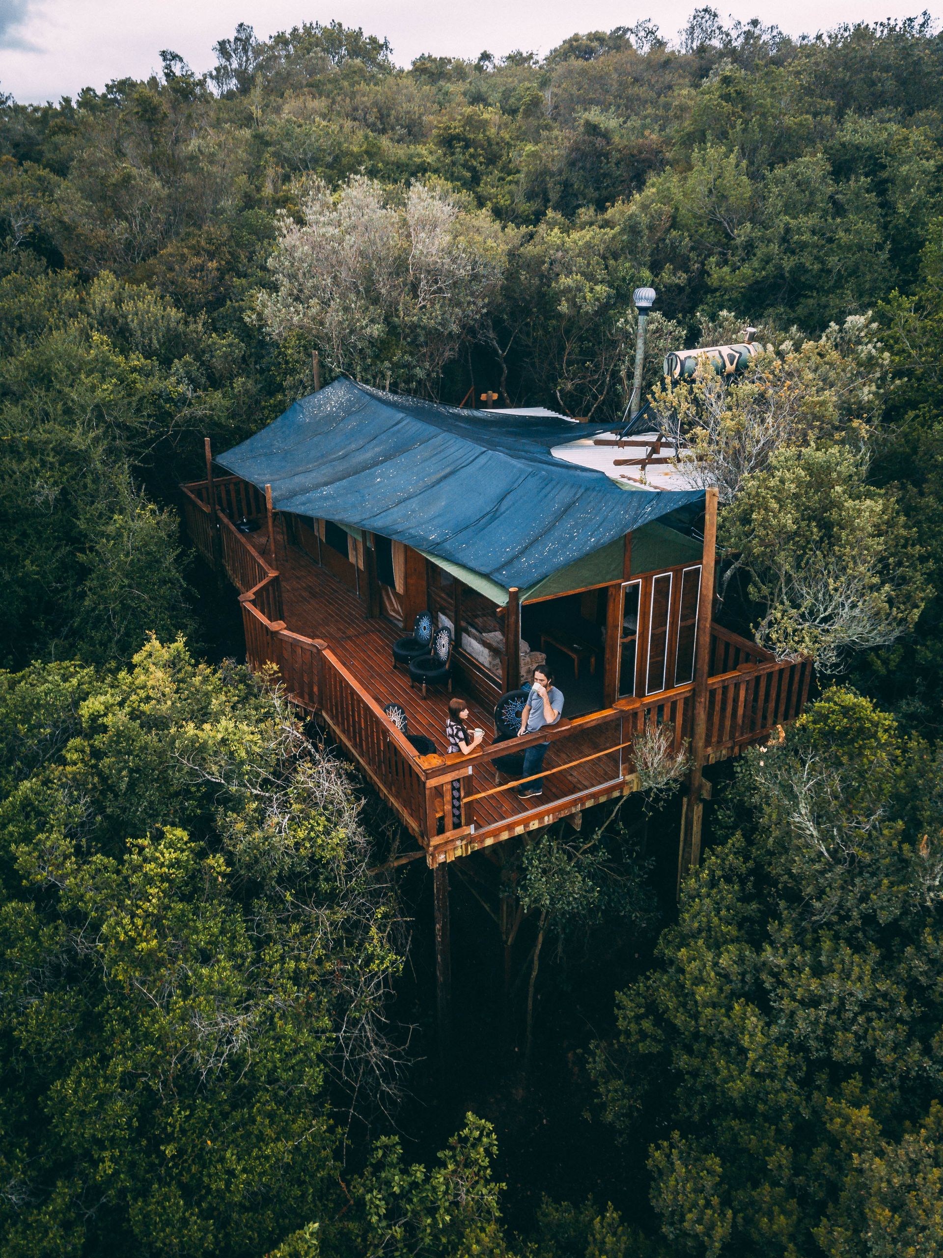 Wooden cabin with a deck in a lush forest.