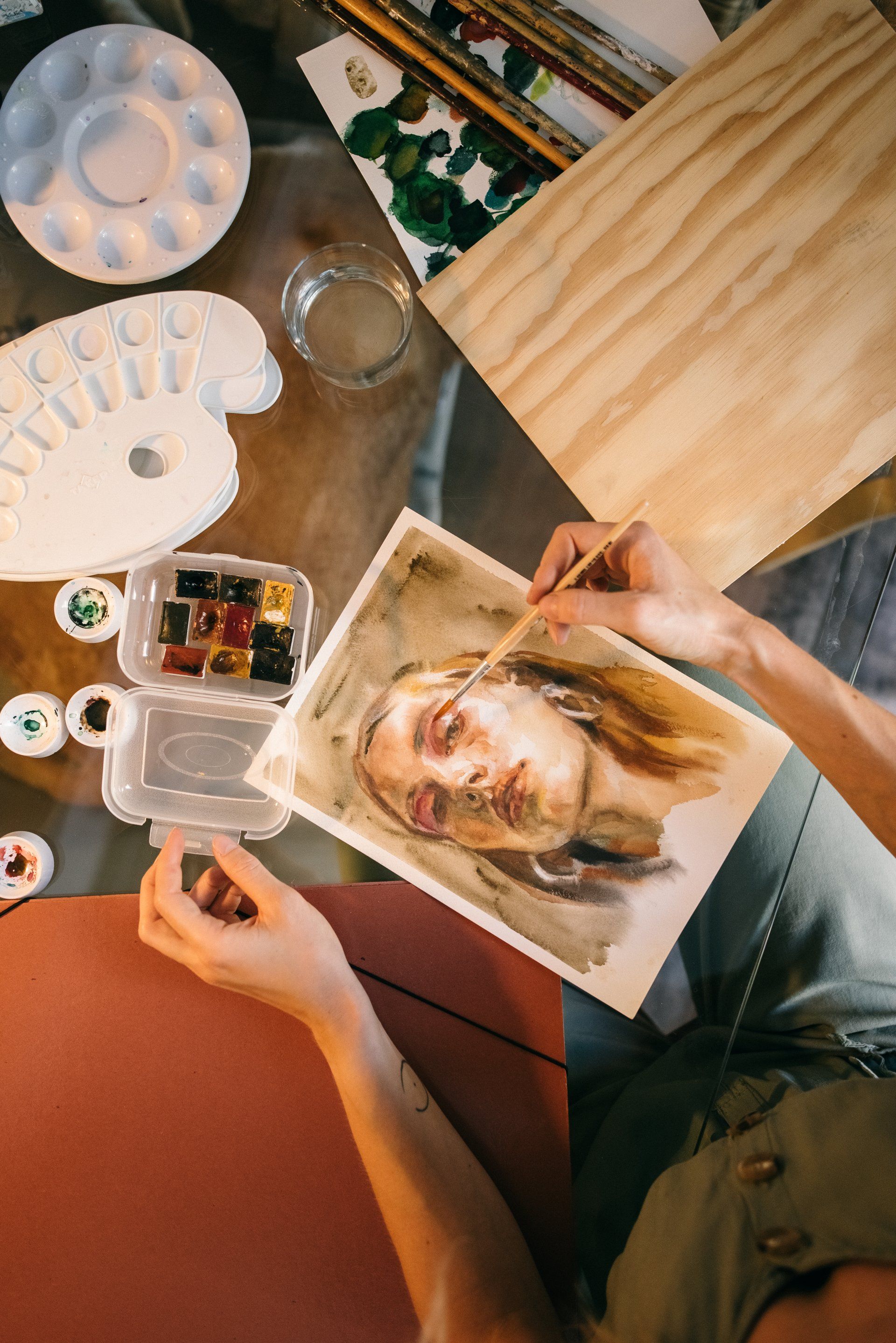 A woman is sitting at a table painting a portrait of a woman.