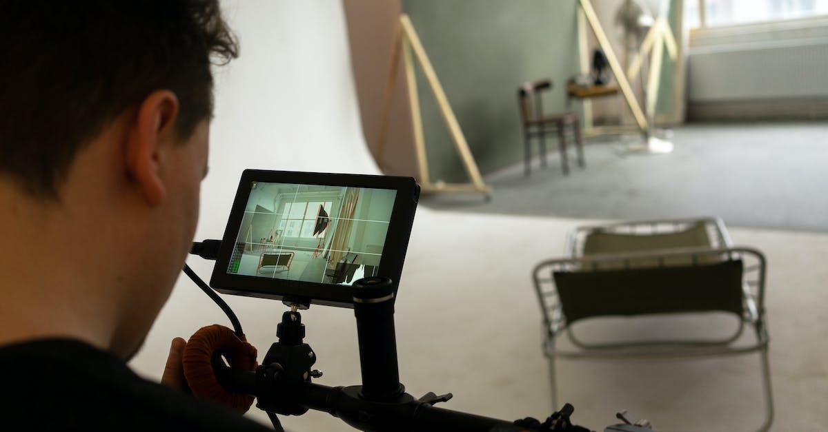 A man is looking at a screen with a chair in the background.