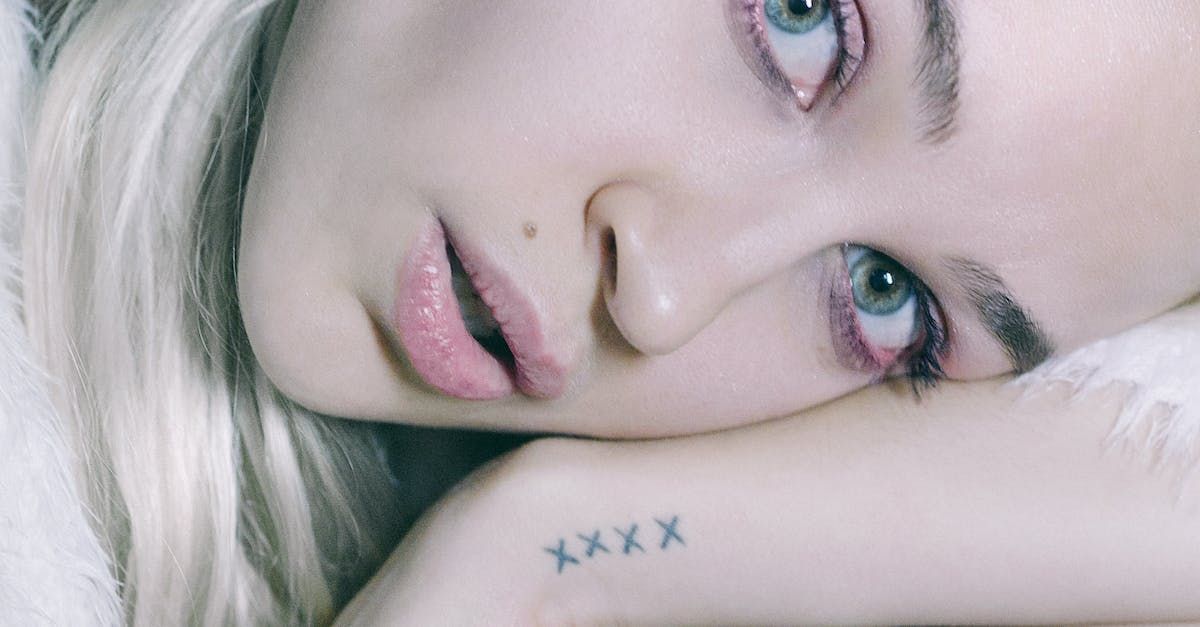Een close-up portret van een persoon met blond haar die zijn kin laat rusten op een hand met een 