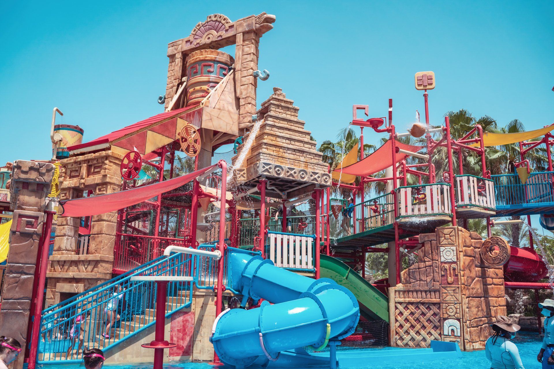 A water park with a slide and a pyramid in the background.