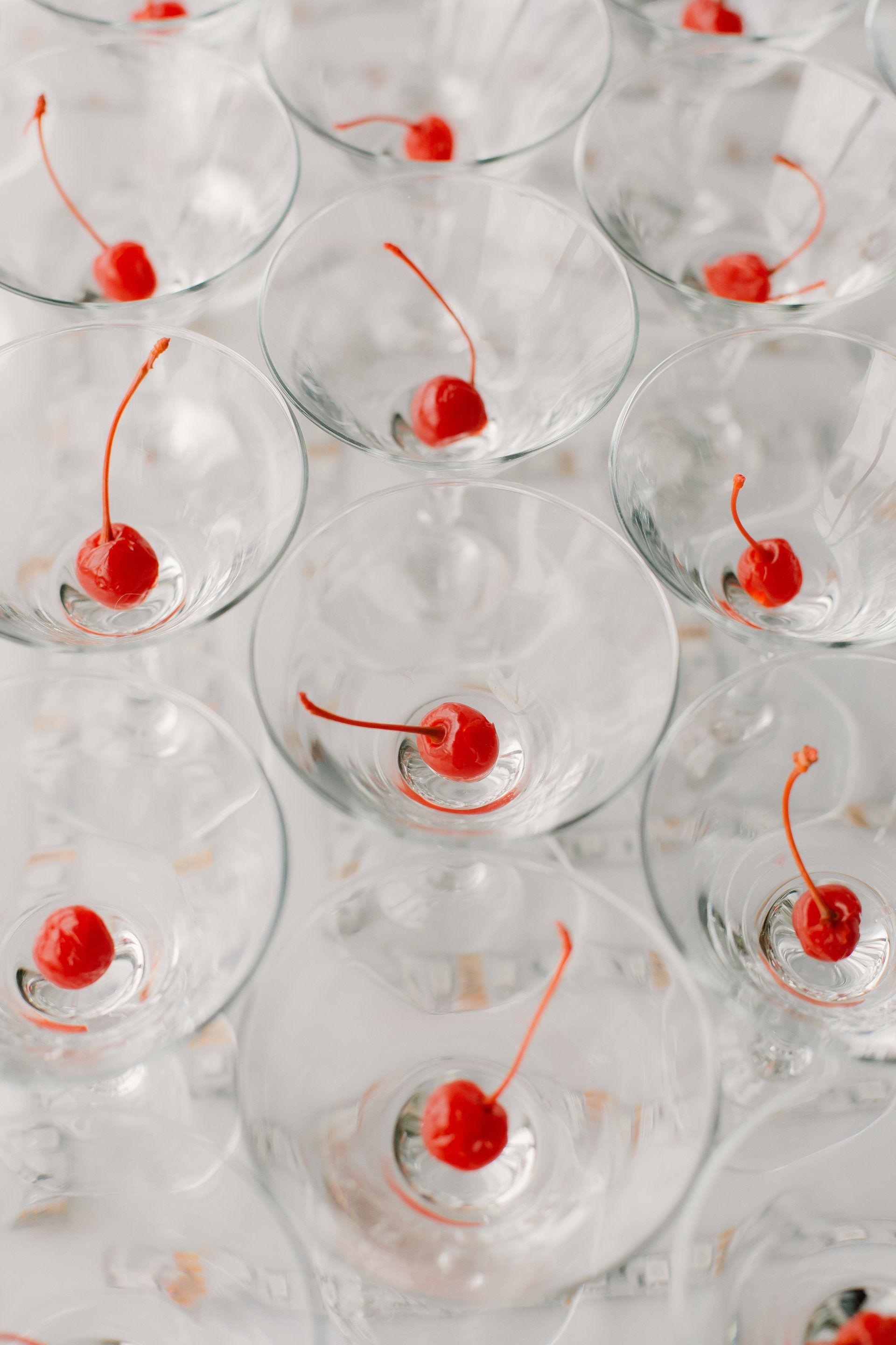 A stack of martini glasses with cherries on top of them.