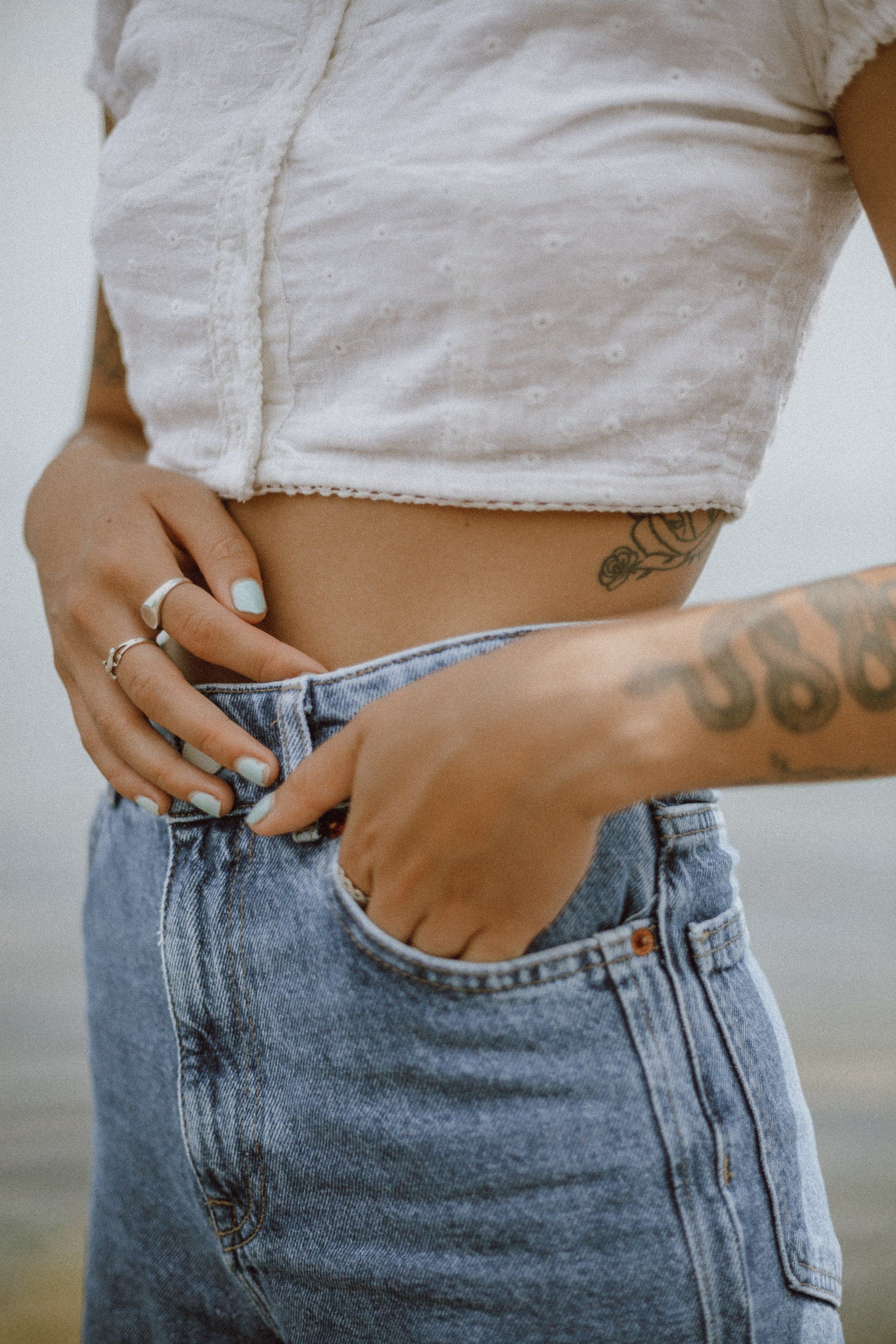 A woman with a tattoo on her arm is putting her hand in her pocket.