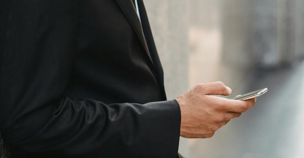 A man in a suit is holding a cell phone in his hands.