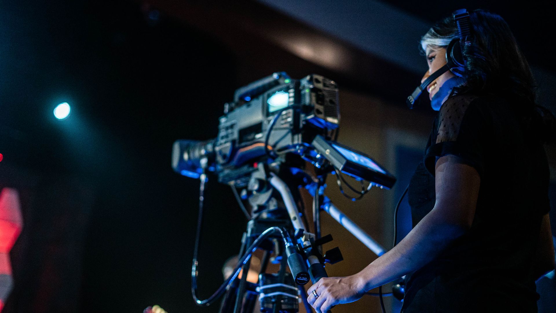 A woman is standing in front of a camera on a tripod.