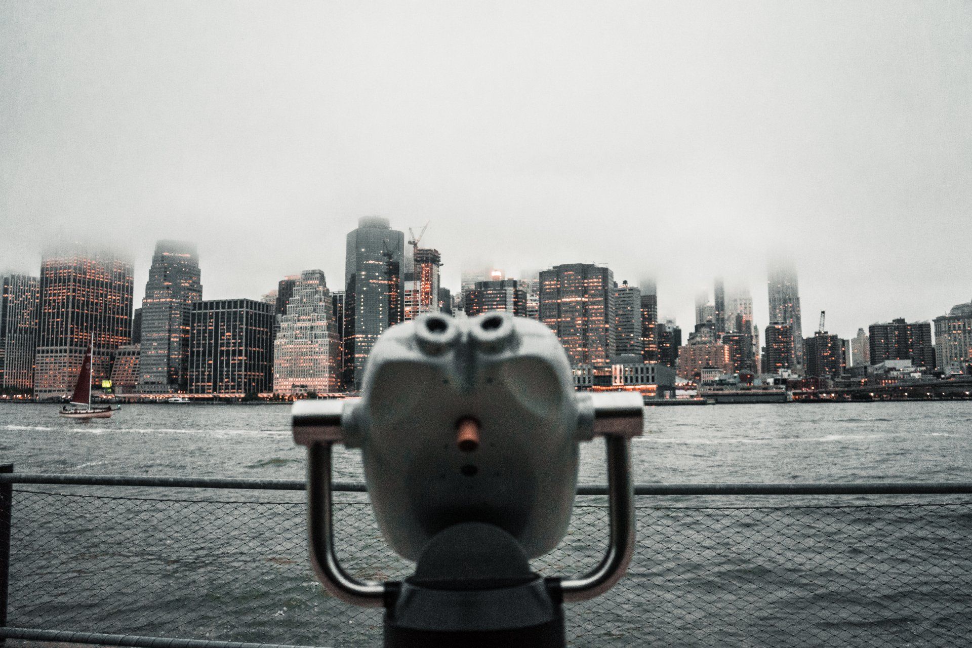 a pair of binoculars looking out over water at a city skyline .