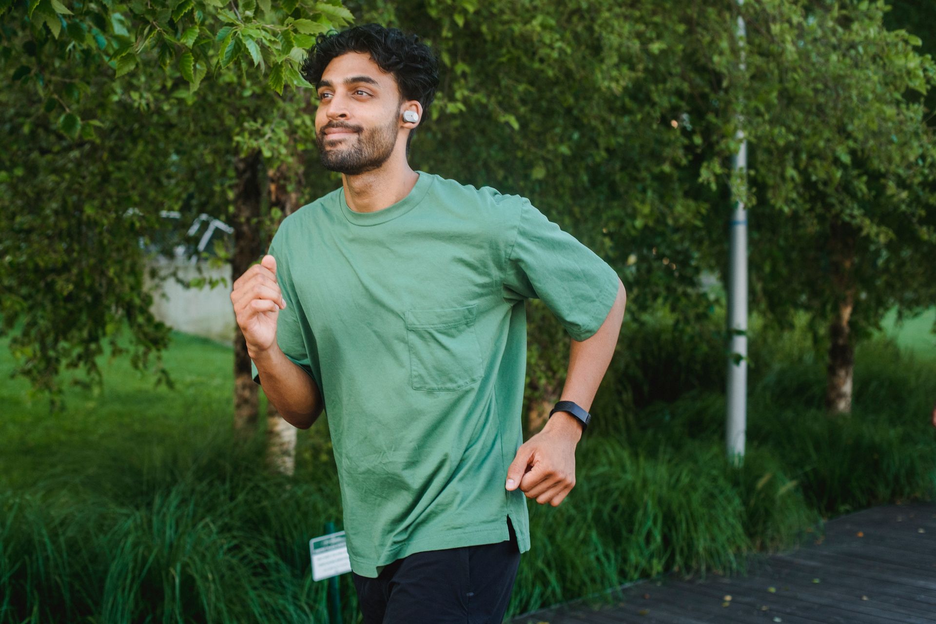 A man in a green shirt is running in a park.