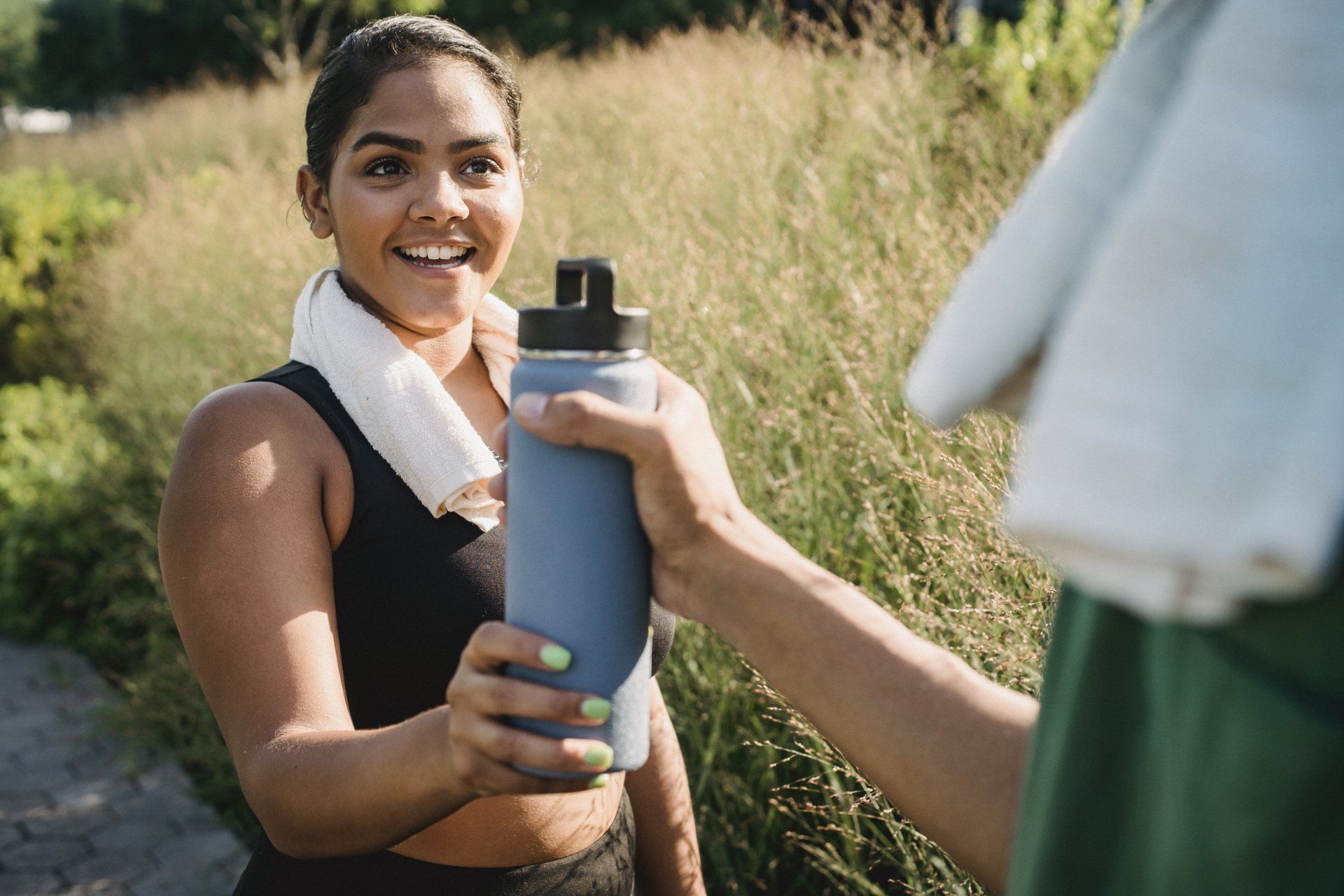 A woman is holding a water bottle and talking to a man.