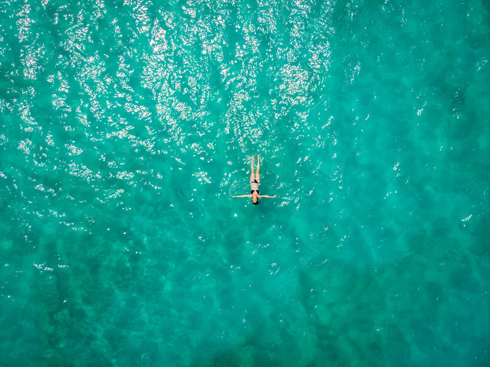 Uma vista aérea de uma mulher flutuando de costas no oceano.