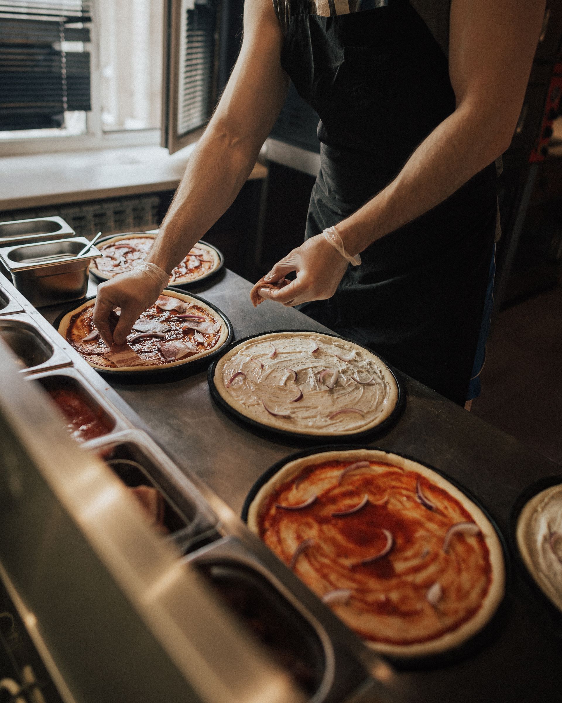 a person is preparing pizzas in a kitchen .