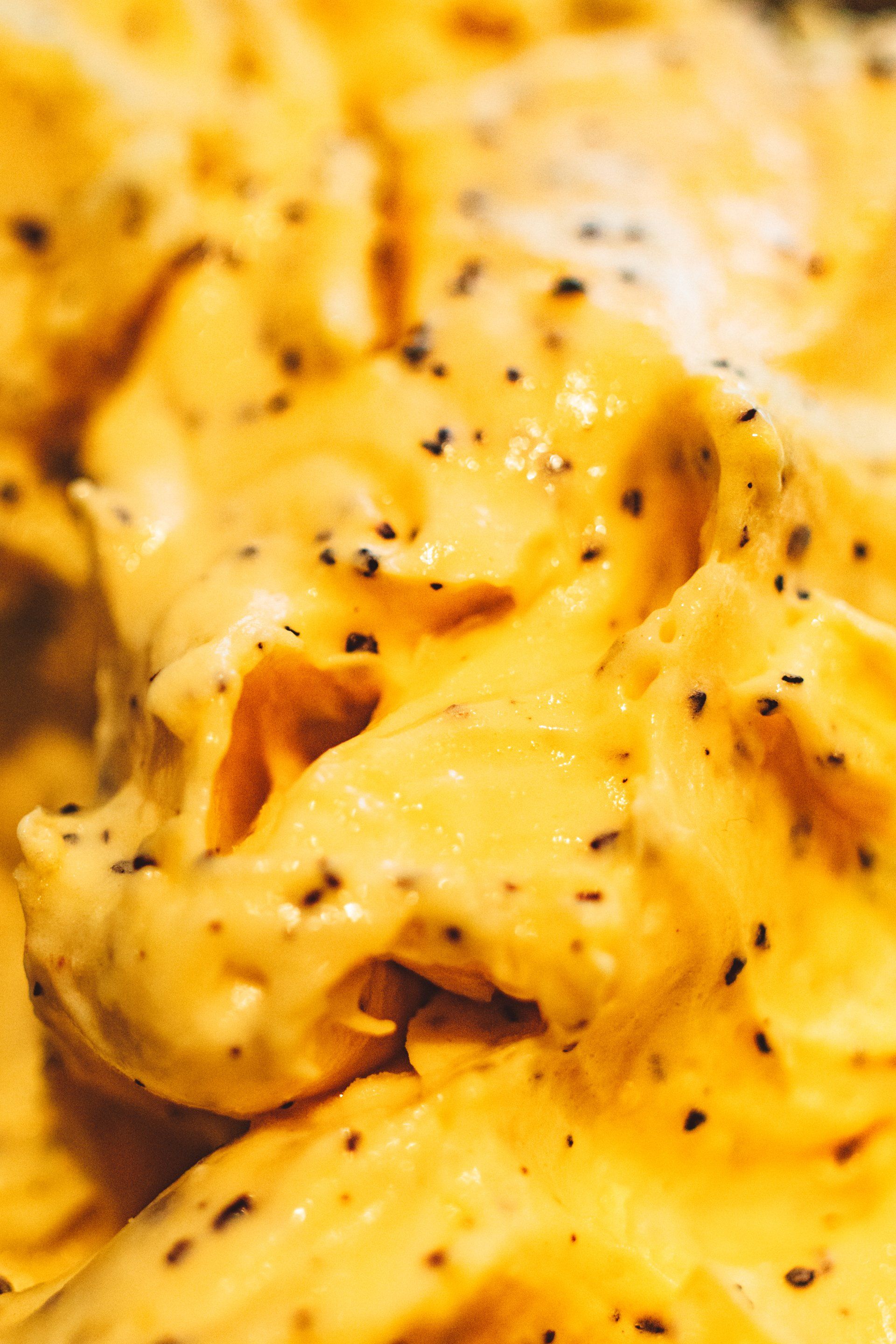 A close up of a yellow sauce with black pepper.