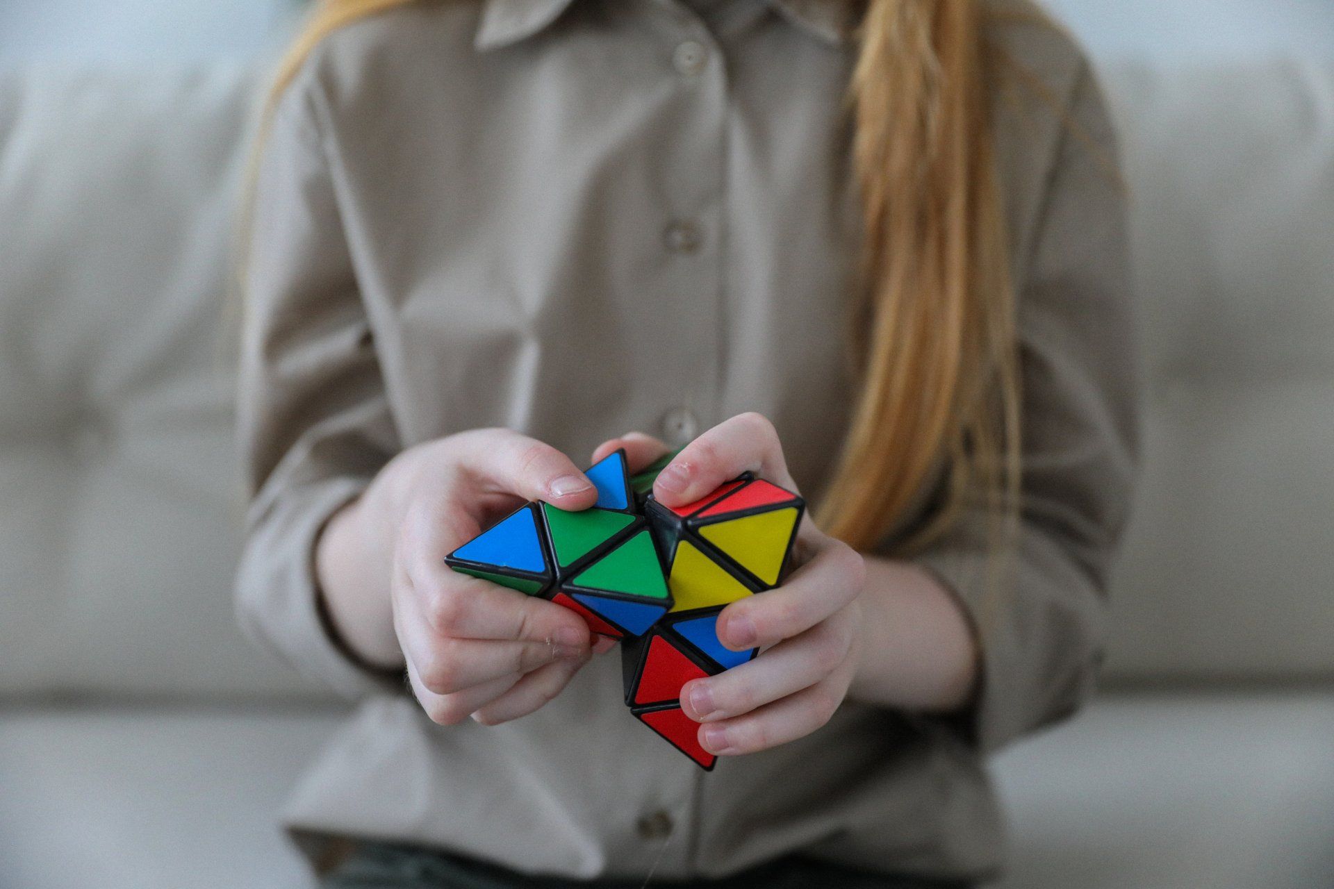 Eine Person hält auf einem Sofa ein buntes geometrisches Puzzle mit beiden Händen.