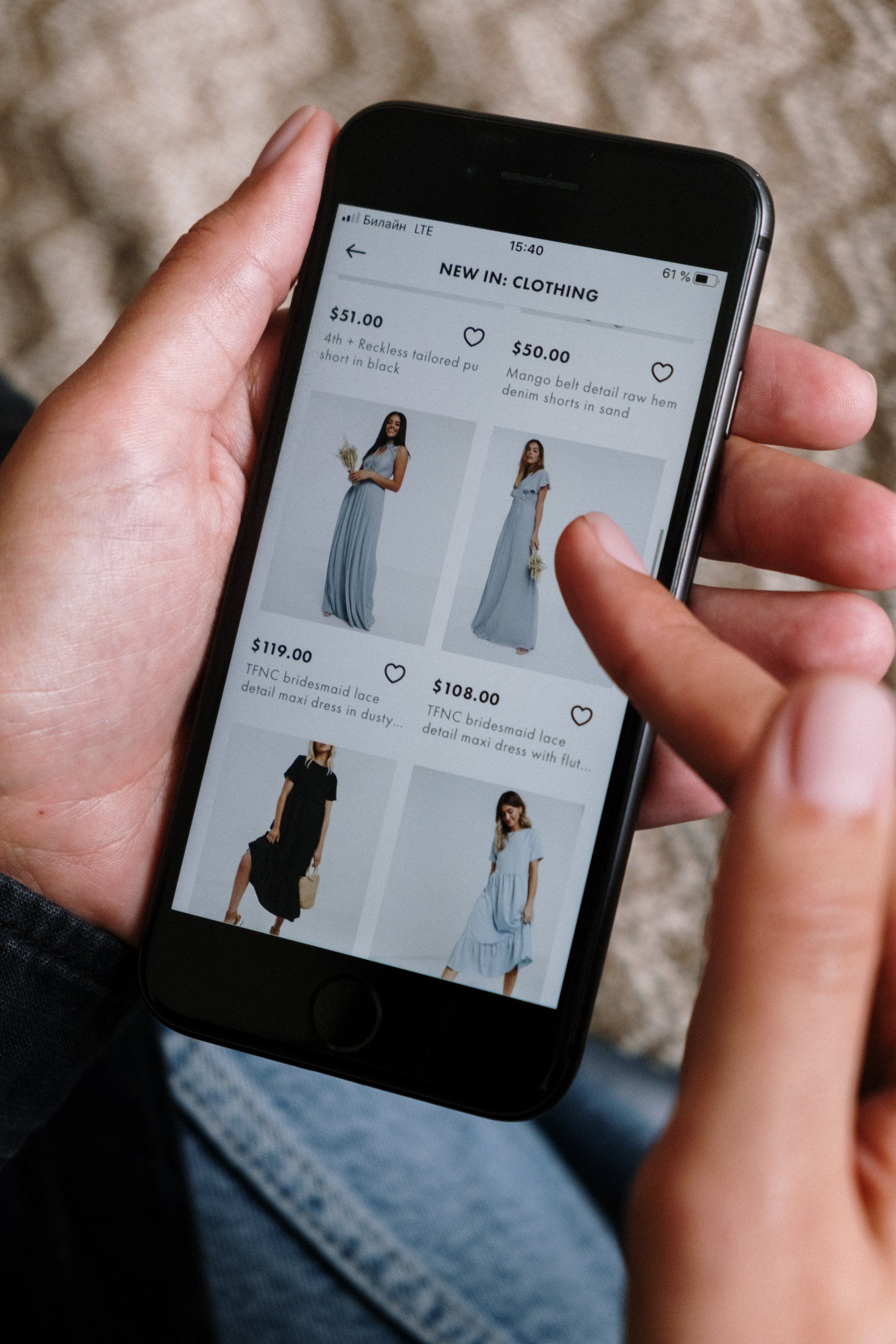 Person holding phone displaying clothing options, browsing online.