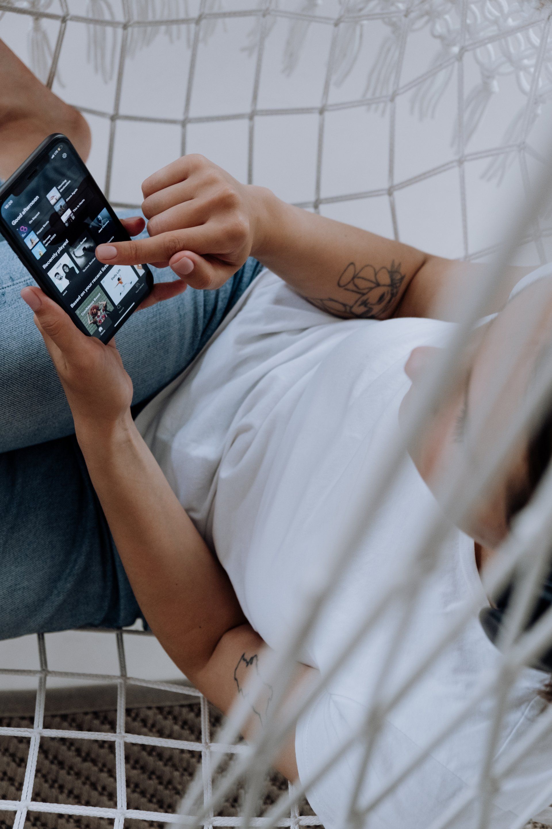 Una persona è sdraiata su u'amaca e usa un telefono cellulare