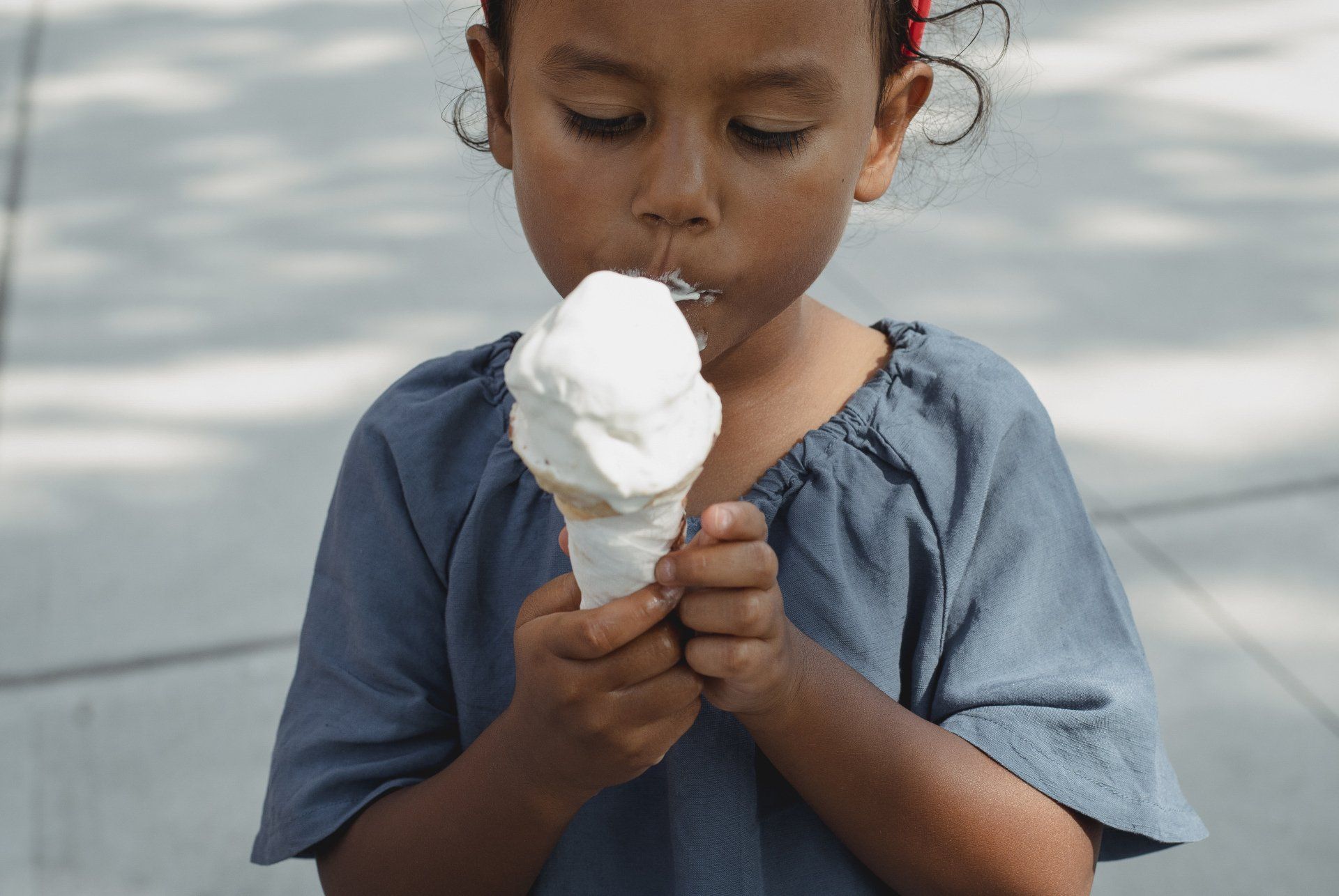 Child eating a white ice cream cone against a gray background. Grasshopper Farms Knightdale, NC