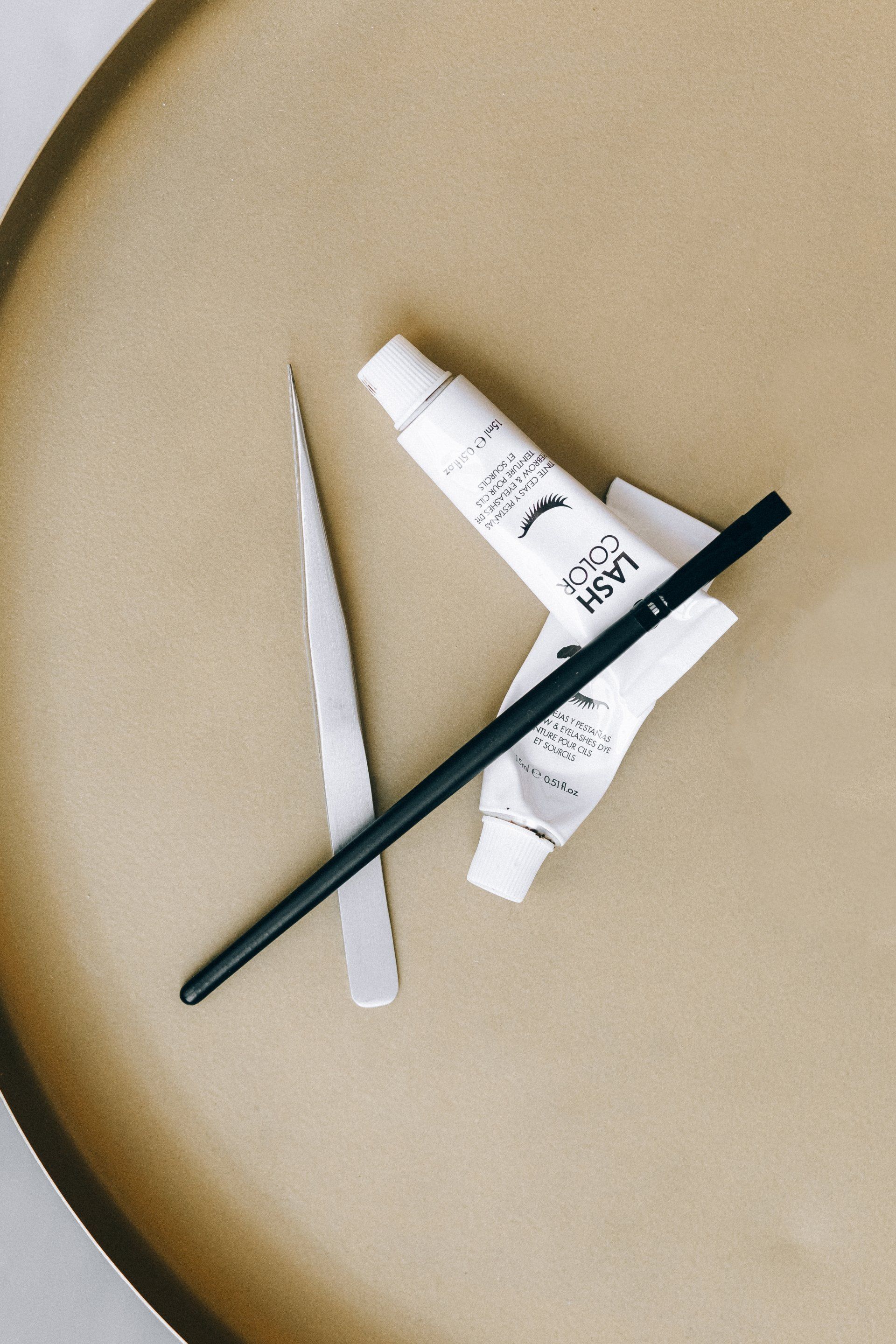 Paintbrushes and a white tube of paint on a tan surface