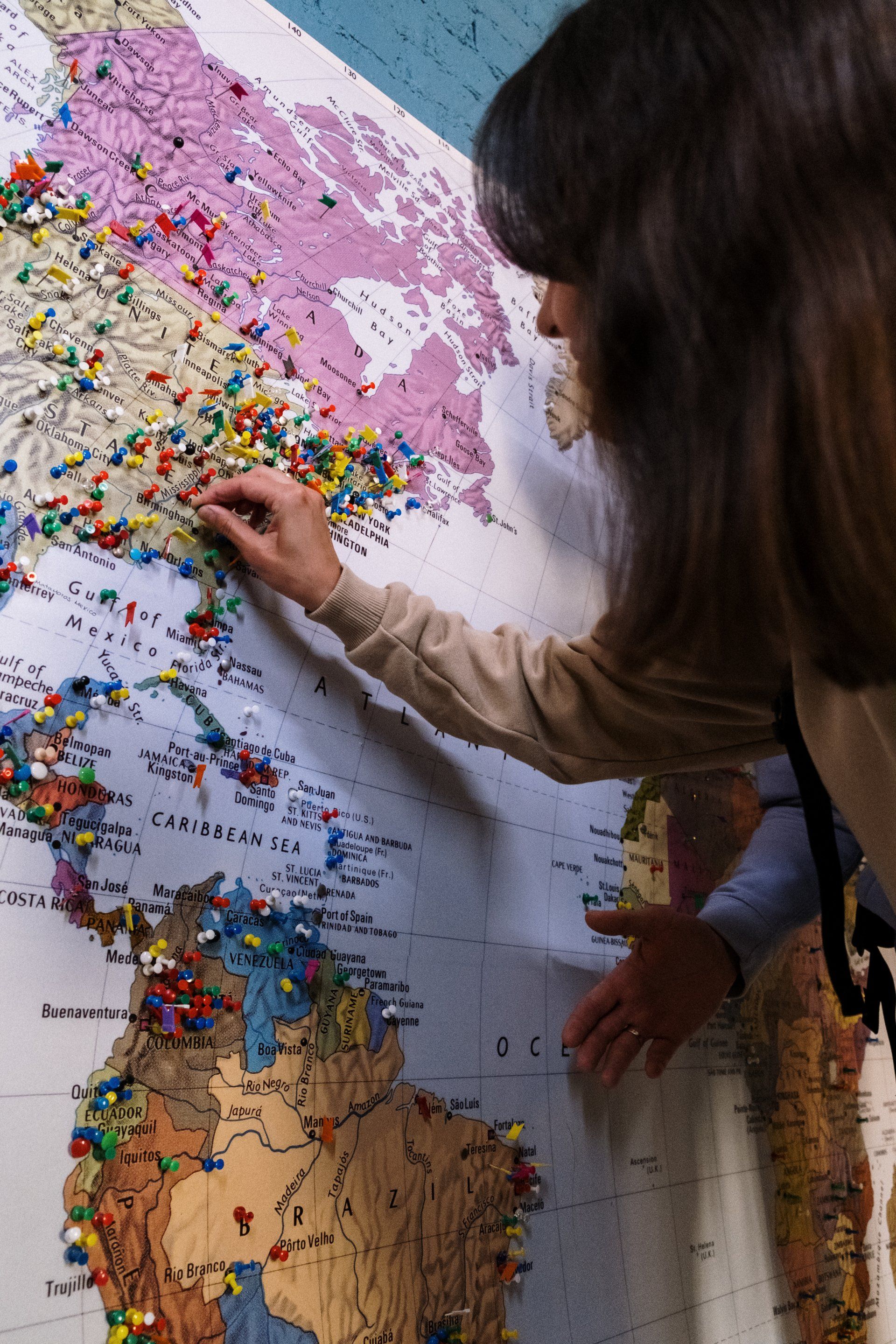 A woman is pinning pins on a map of the world
