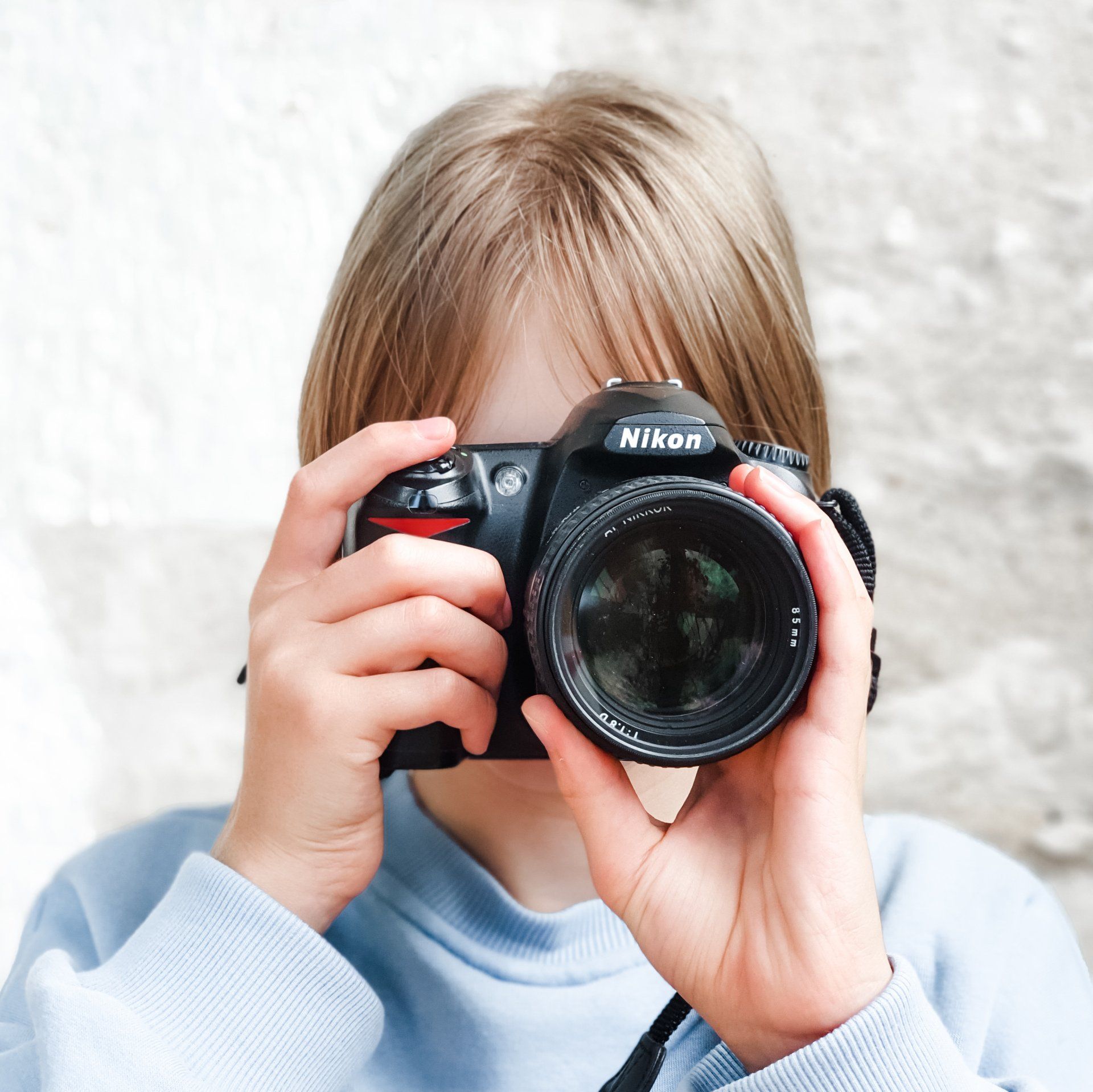 A young girl is taking a picture with a nikon camera