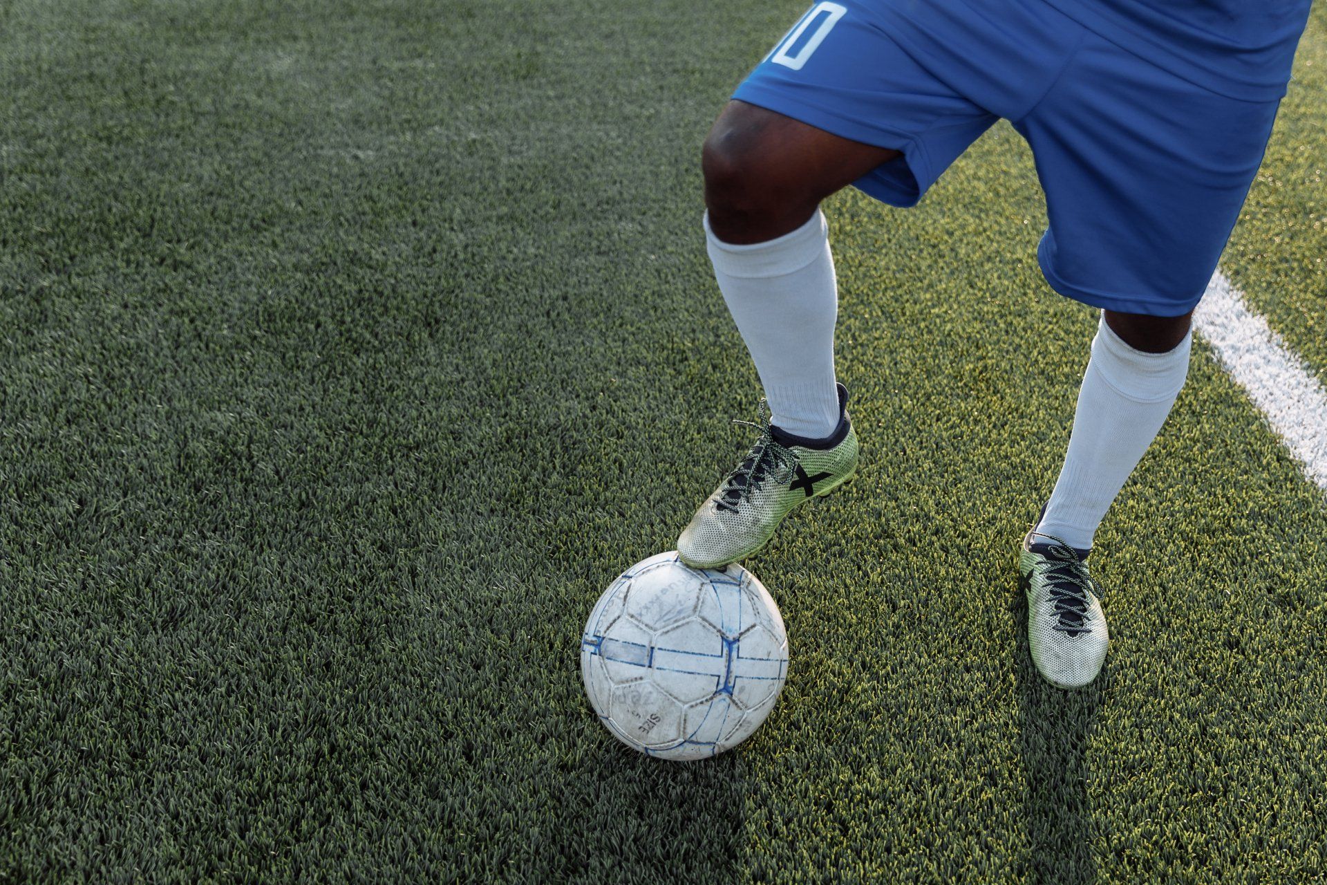 Een voetballer schopt een voetbal op een veld.