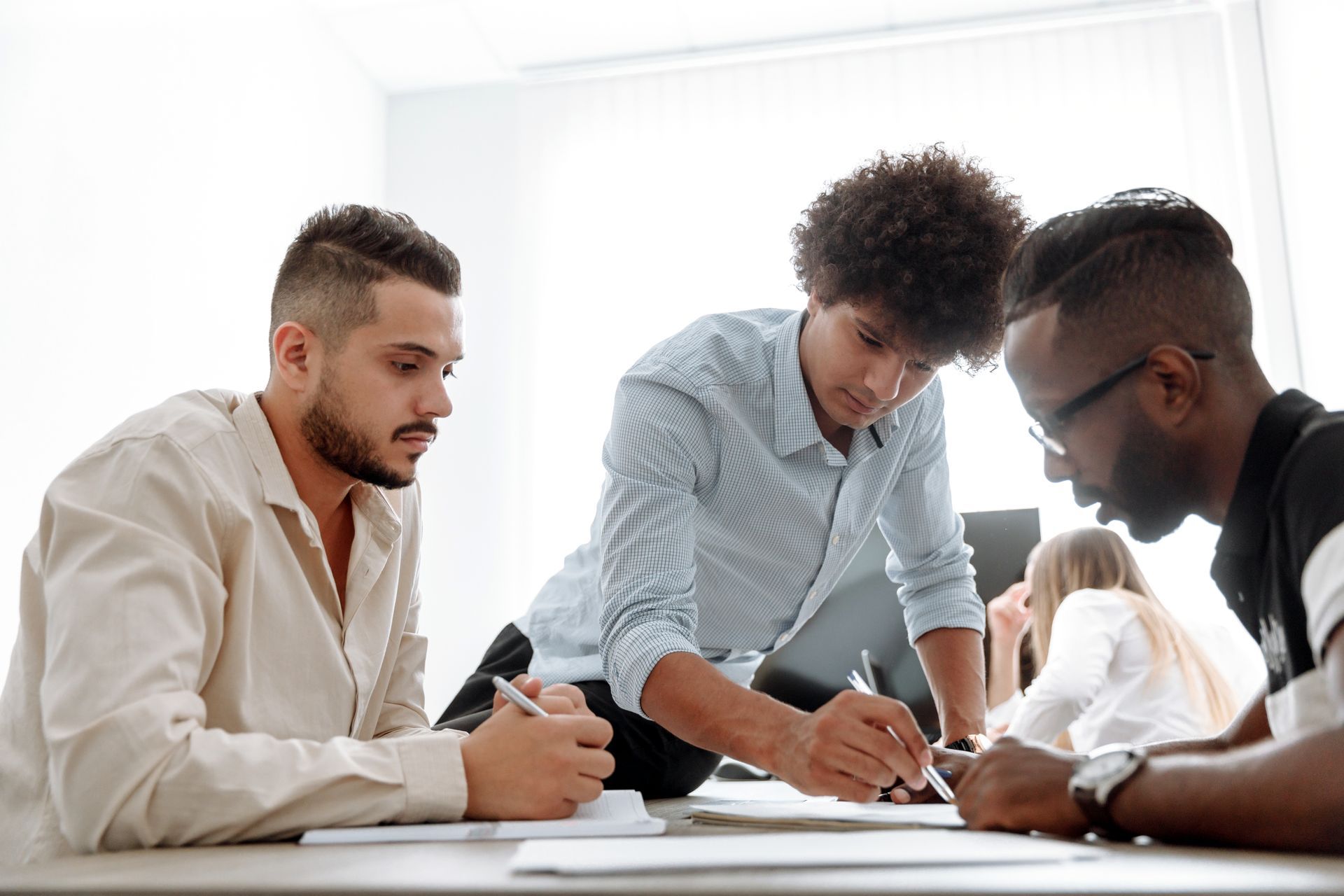 un groupe de jeunes hommes sont assis autour d' une table et travaillent sur un document
