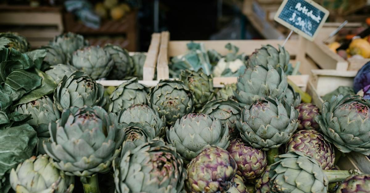 A close-up view of fresh green artichokes piled in wooden crates at a market.