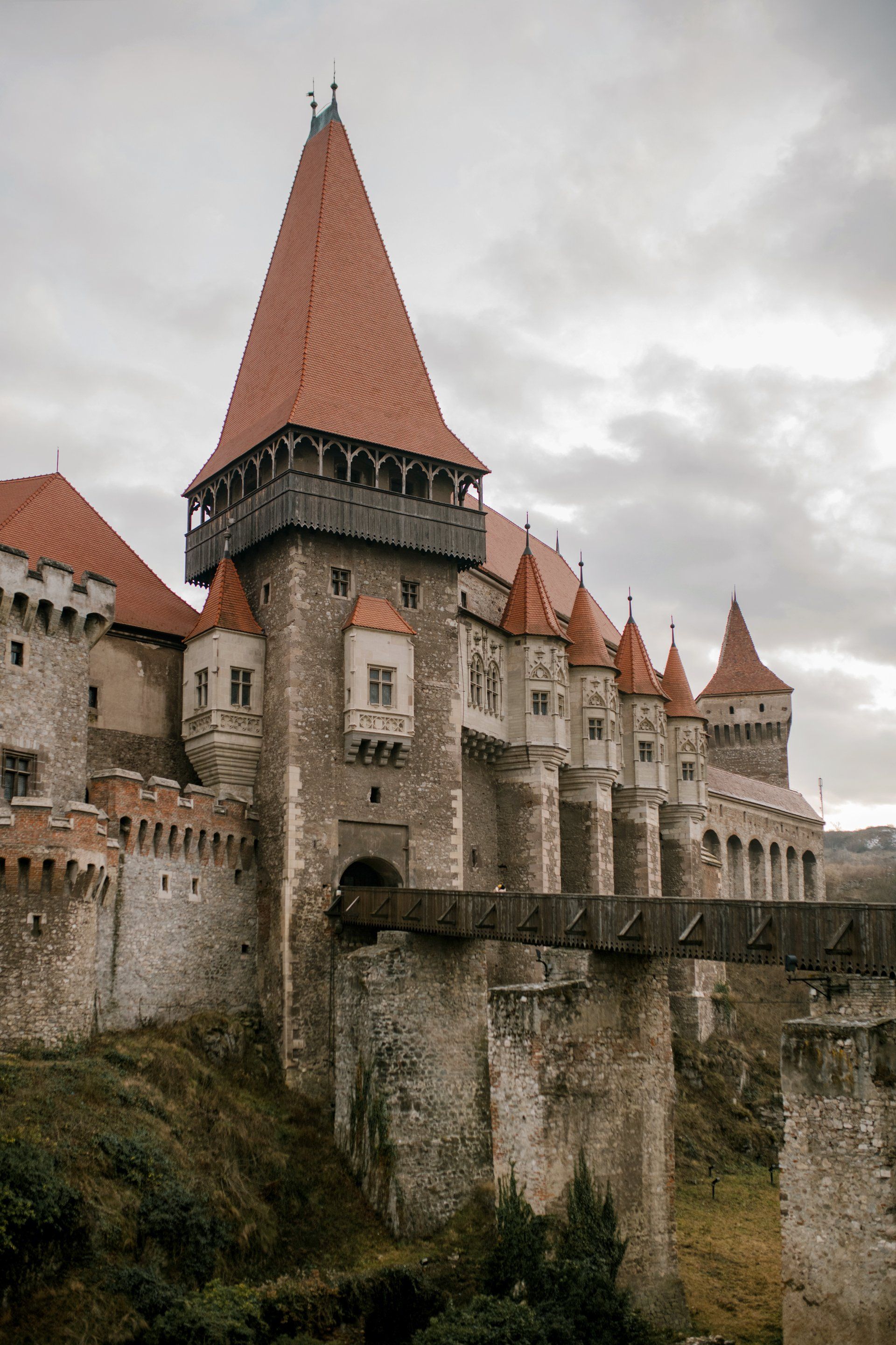 A large castle with red tiled roofs and a bridge in front of it.
