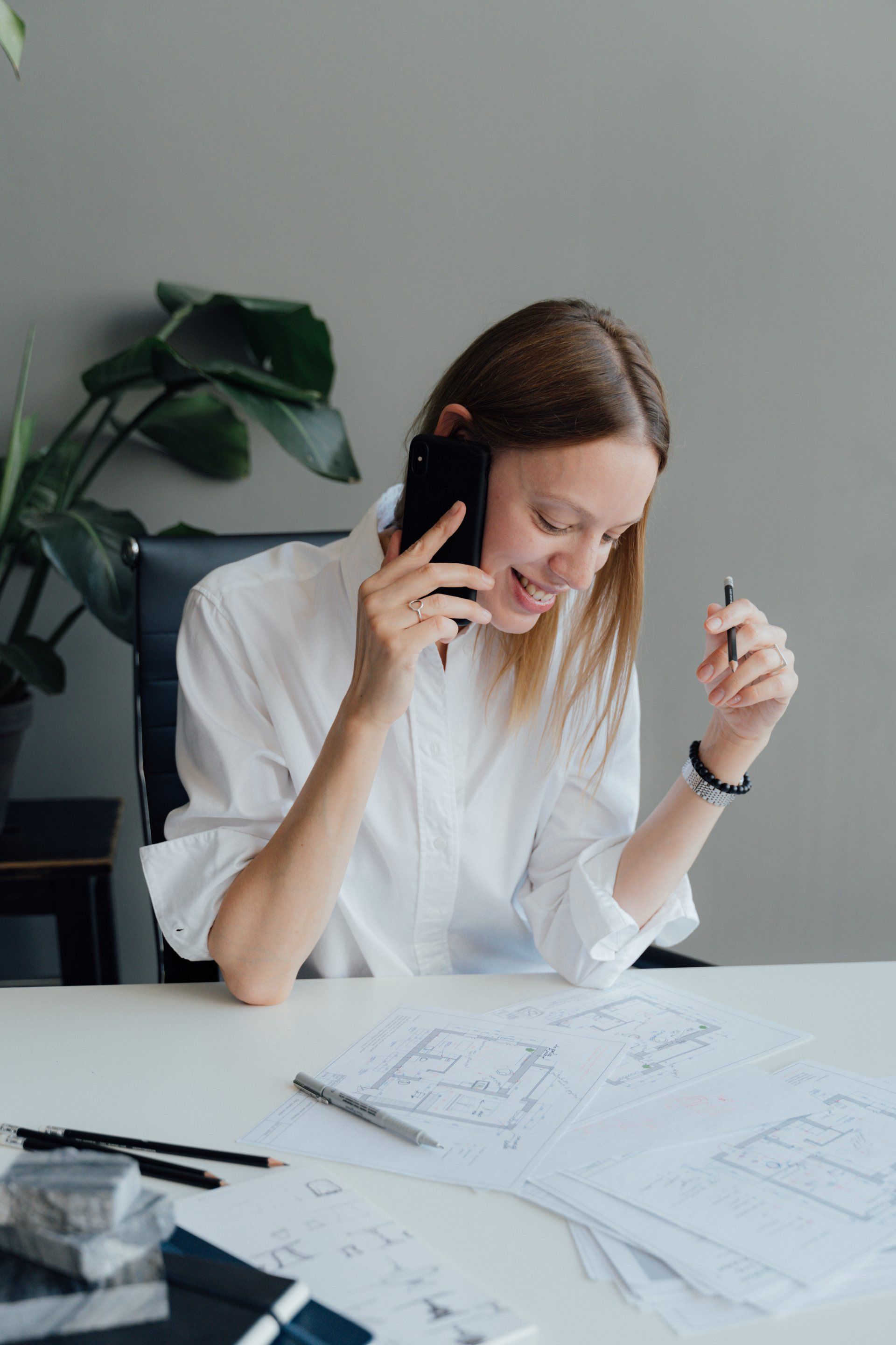 A woman is sitting at a desk talking on a cell phone.