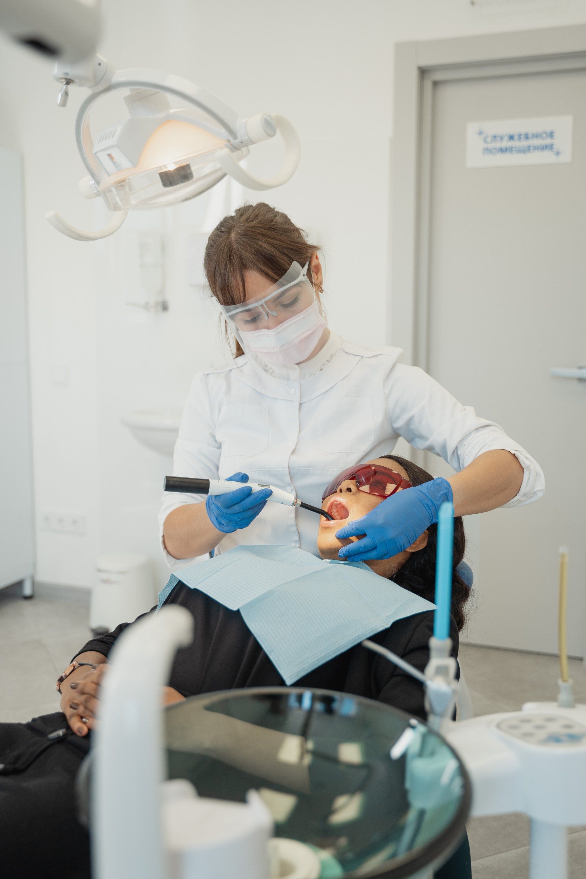 A dentist is examining a patient 's teeth in a dental office.