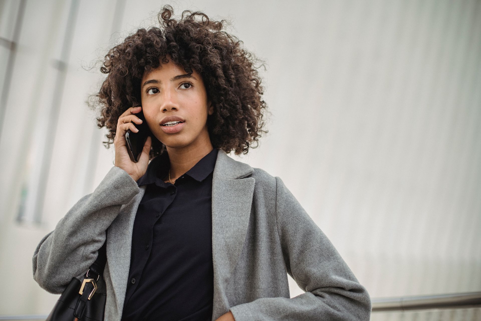 a woman with curly hair is talking on a cell phone .
