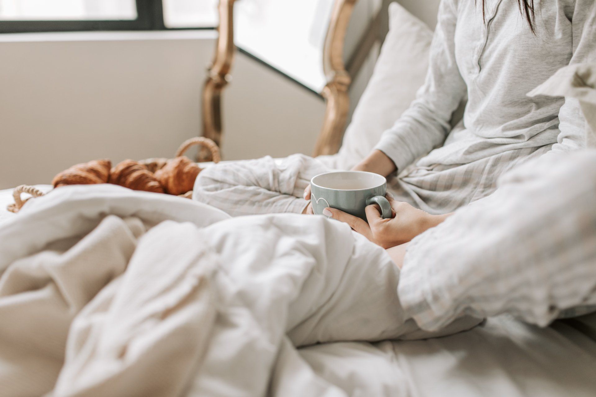 Women with a cup of coffee and blankets in bed