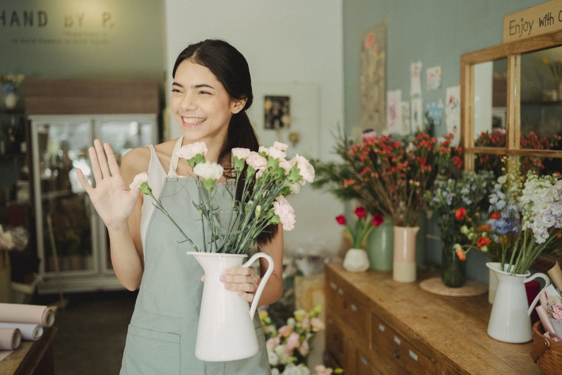 A woman is holding a vase of flowers in a flower shop.