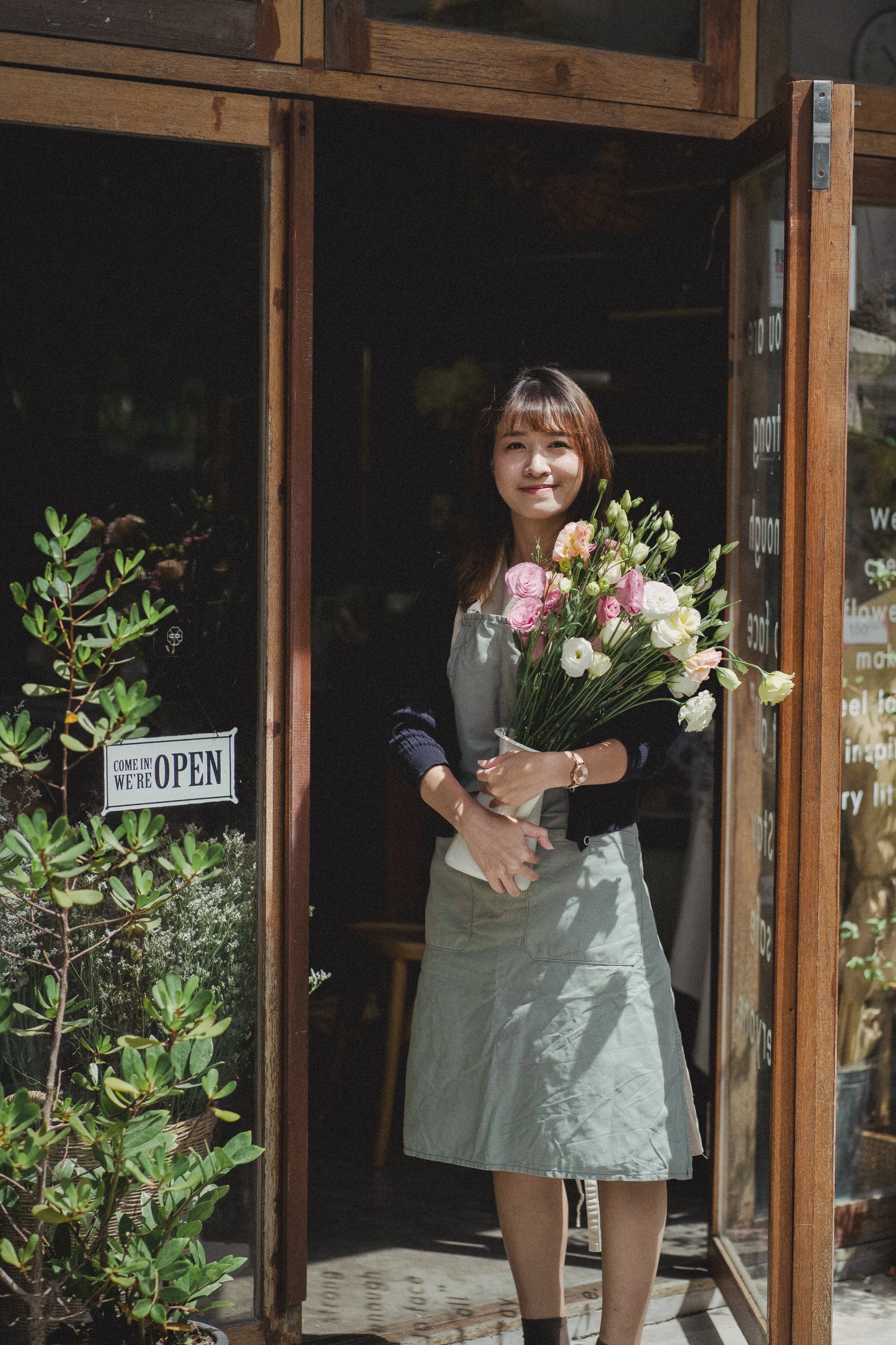 A woman is holding a bouquet of flowers in front of a door.