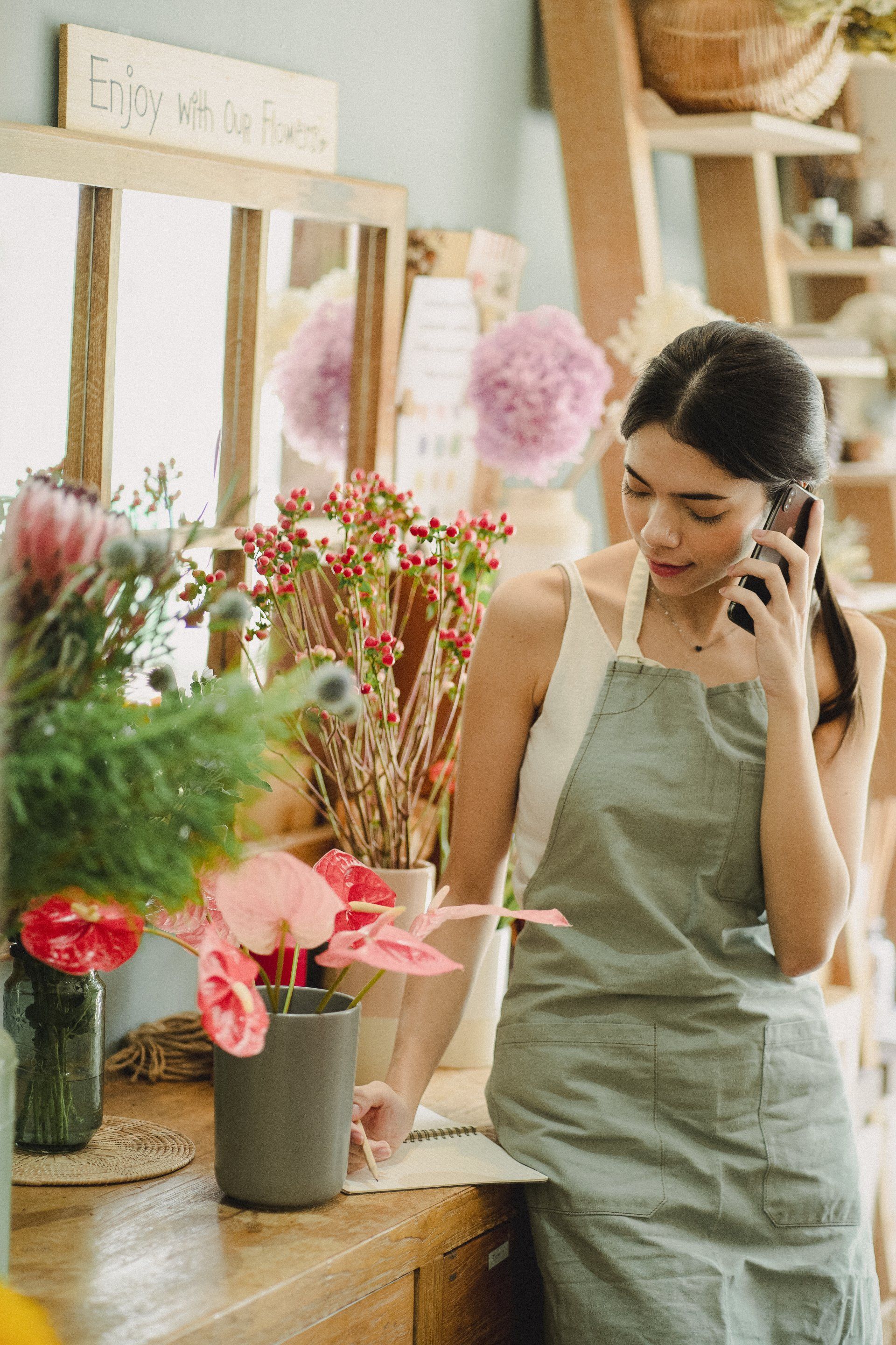 A woman is talking on a cell phone in a flower shop.