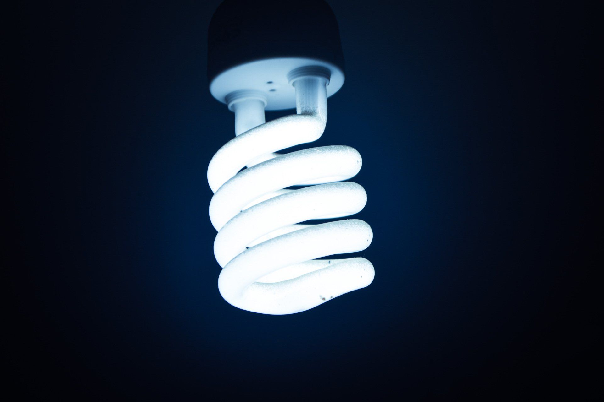 A spiral light bulb is lit up in the dark