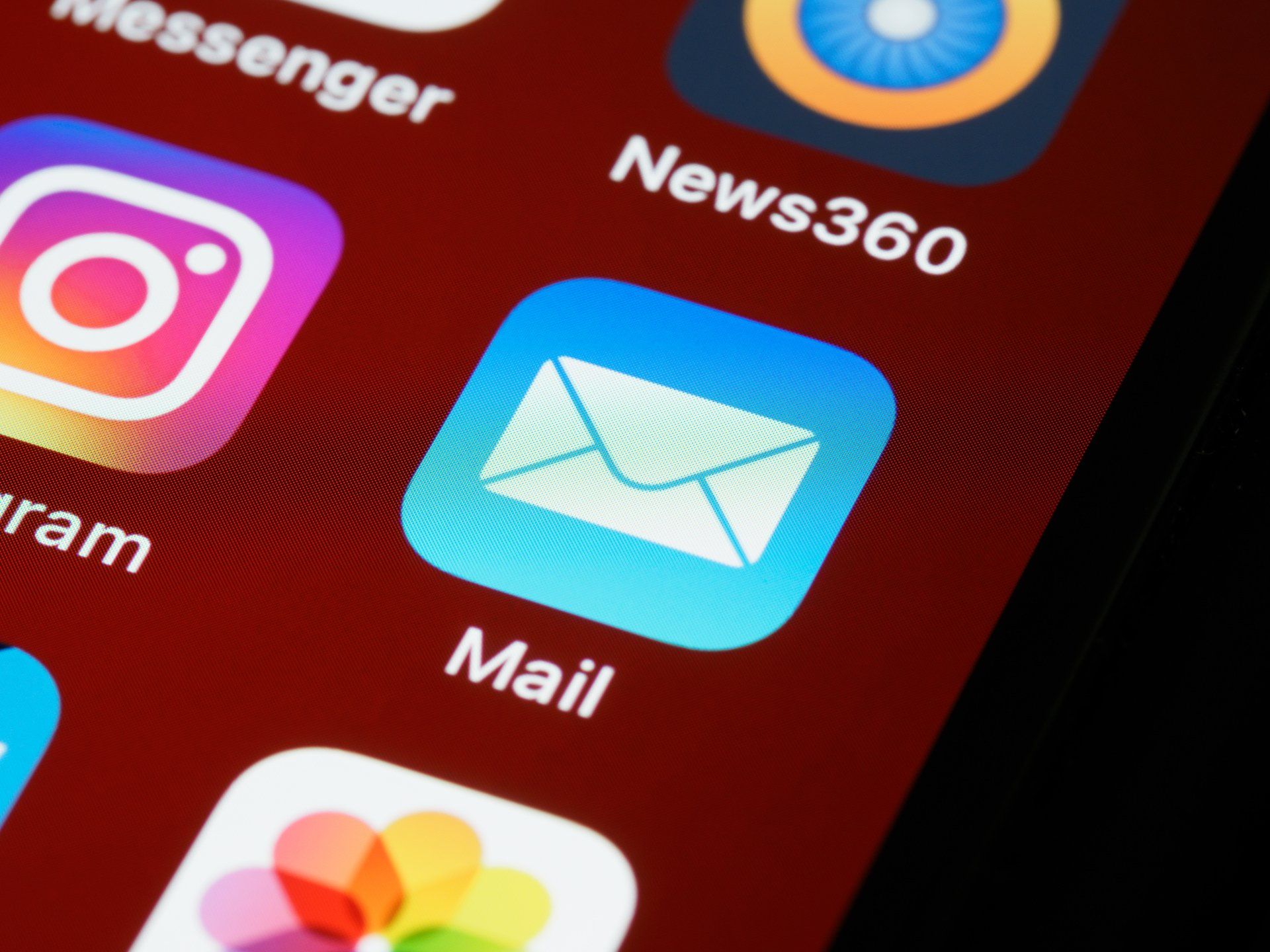 Close-up of a phone screen showing the Mail app icon, a white envelope on a blue background.