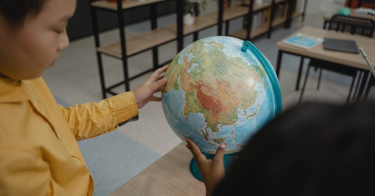 A young boy is holding a globe in his hands in a classroom.