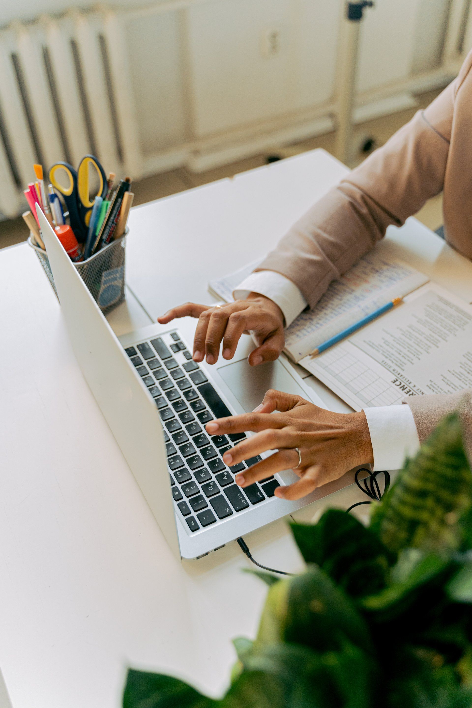 A woman is typing on a laptop computer at a desk.