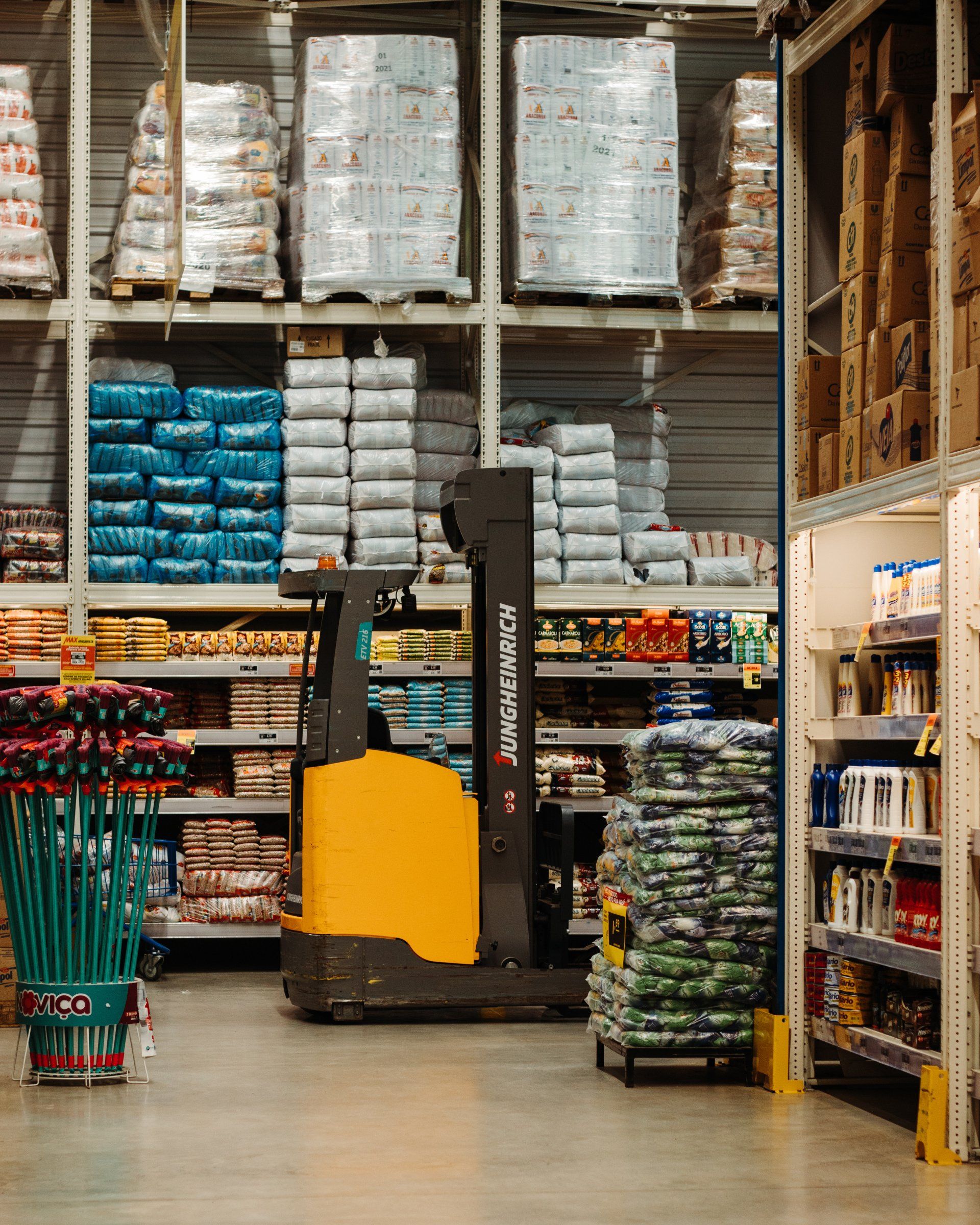 A forklift is driving through a warehouse filled with lots of products.