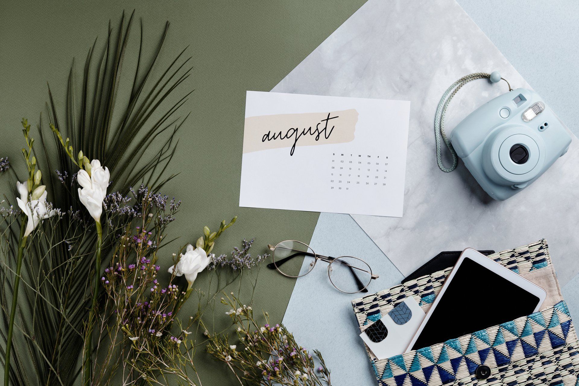 a card with the word august written on it is surrounded by flowers and a camera .