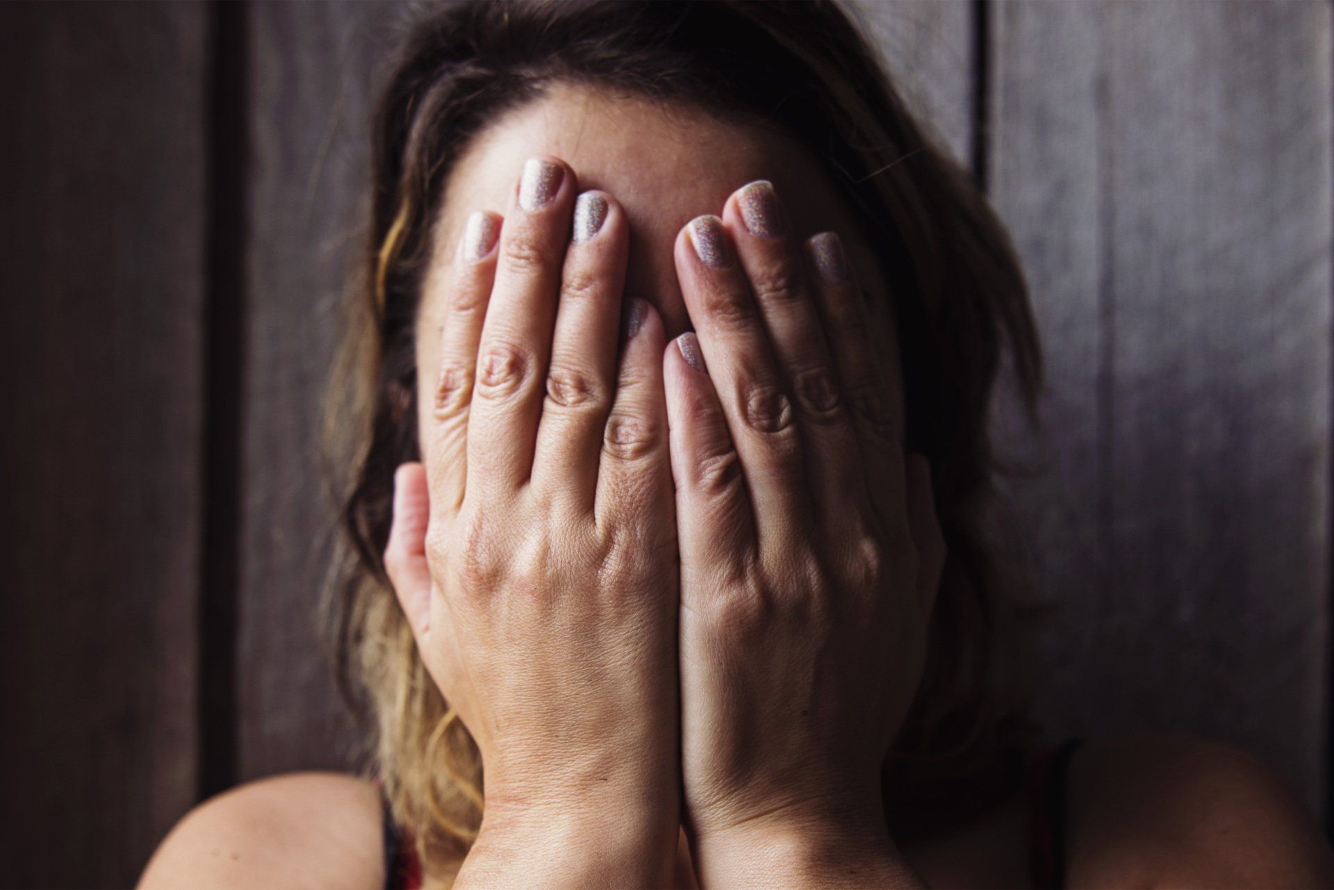A woman is covering her face with her hands.