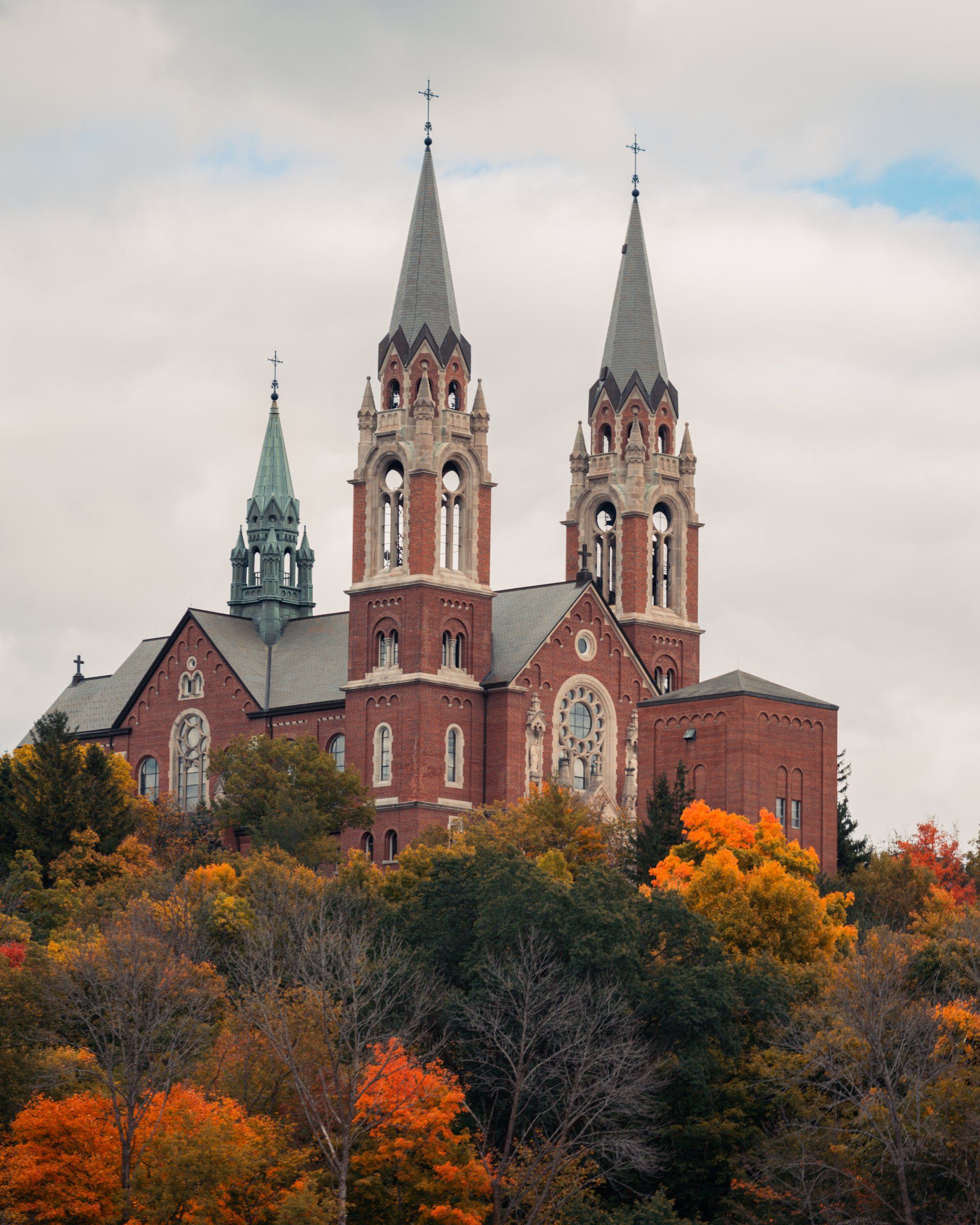 A large brick church with two towers surrounded by trees