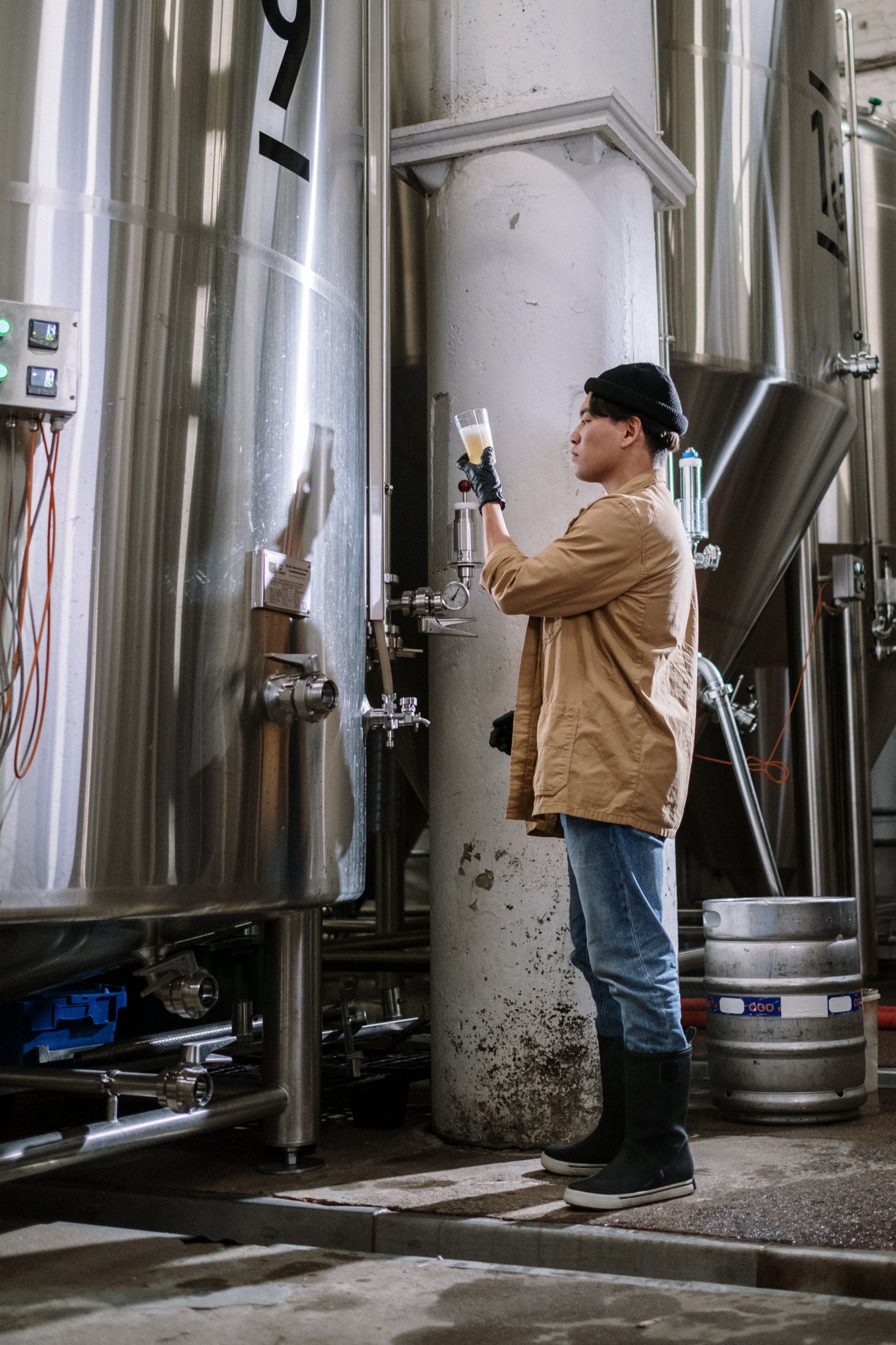 A man is pouring beer into a tank in a brewery.