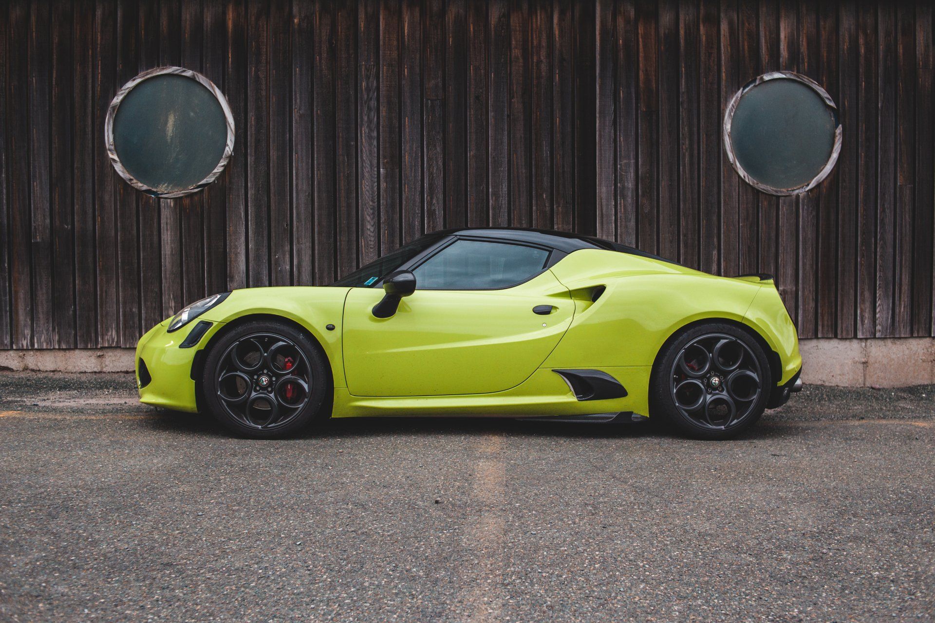 A yellow sports car is parked in front of a wooden building.
